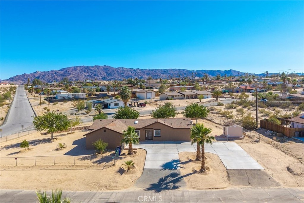 Welcome to 73883 Playa Vista Dr, a beautifully maintained and upgraded 3 bedroom 3 bath home located in the quiet and desirable Ben Hunter neighborhood of 29 Palms. From the inside out, this home boasts utmost pride in ownership. Featuring 2,112 square feet of living space, this property is nicely situated on a corner lot with .5 acres of land and is located just minutes to downtown, schools, shopping, eateries, the marine corps base, JT National Park & more. As you arrive you'll notice the convenient wrap-around driveway, mature palm-trees, attached 2 car garage and fully fenced yard. As you step inside the open-concept living space you'll find high ceilings with ceiling fans, warm wood-like laminate flooring throughout, new dual pane windows, recessed lighting and fresh paint both inside & out. Just off the living room is the kitchen and dining area complete with ample cabinet & counter space, stainless steel appliances and a north facing window that lets in an abundance of natural light. The primary bedroom features an oversized walk-in closet and TWO ensuite bathrooms, one of which has been gorgeously remodeled with a dual sink vanity, corner soaking tub & a spa-like walk-in shower with a rainfall shower-head. There is also a 3rd hall bathroom, 2 additional bedrooms and a sizable indoor laundry room. Not to mention, this home has a New HVAC system plus leased solar to keep costs low year-round (buyer to assumed solar lease, $151 a month with no annual increase). That's just the inside, outside you'll find a lovely landscaped yard with 10 mature trees & 4 fruit-bearing trees, a tuff shed for extra storage, a large covered patio, a paver stone retaining wall and plenty of space to entertain or relax around a firepit on a starry desert night. A meticulously maintained home like this rarely becomes available, come take a look & let this home's charming allure do the rest. Your new desert home, investment property or weekend retreat awaits!