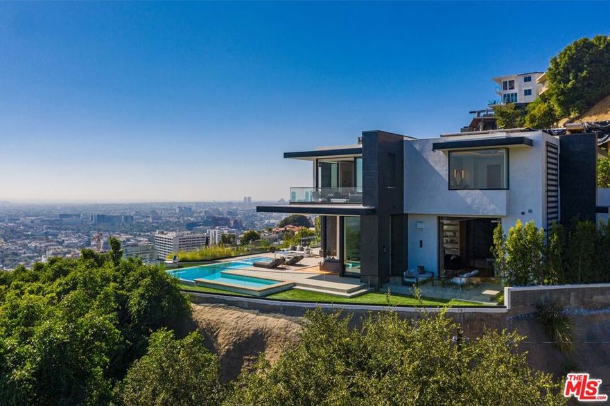 Quintessential Sunset Strip Modern with A+ views from downtown to the ocean! Walled and gated motor court, perfect for the high-profile privacy/security conscious. Double height entry. Versatile living rooms lead to vanishing walls of glass opening to wraparound outdoor space featuring an infinity-edge L pool, spa, firepit. Chefs eat-in kitchen with Gaggenau appliances, marble countertops, butler's pantries & double island. The primary suite features a sitting room, dual bathrooms, dual walk-in closets, and an outdoor patio. Movie theater, video wall in entertainment room with bar opens out to the view and terrace. Gym or guest suite w/ wet/dry sauna. Off street parking & 3 car garage. Award winning designer Tim Campbell used midcentury modern influences like grand terrazzo, antique brass, warm woods and elegant natural stone. Moments from Sunset yet perched on a promontory.