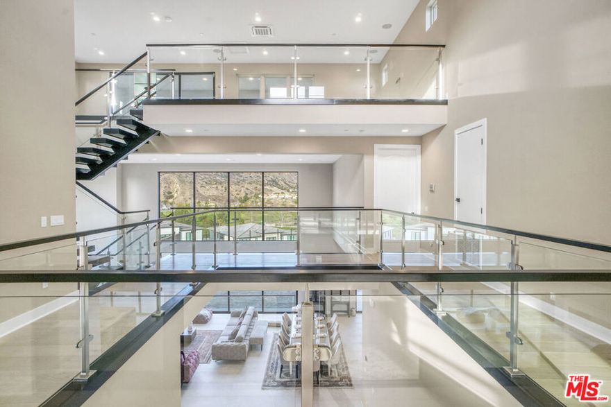 Welcome to this remarkable, luxury three story estate ,"Santi Model" nestled in the prestigious Westcliffe community of Porter Ranch Hills. The design seamlessly combines elegance and practicality, creating inviting spaces ideal for both relaxed family gatherings and sophisticated entertaining. With exquisite finishes, expansive layouts, and carefully selected amenities, every inch of this home has been crafted to offer a refined living experience, ensuring both residents and guests enjoy the perfect balance of comfort and luxury. As you approach, the impressive facade offers a glimpse of the elegance inside. Upon entering, you'll be struck by the grand open-concept design, with soaring ceilings that span all three levels, creating an overwhelming sense of space and grandeur. The oversized stacking doors seamlessly connect the indoor living areas with the outdoors, flooding the interior with natural light and framing breathtaking panoramic views of the city and mountains. This feature not only enhances the visual appeal but also offers a serene backdrop to everyday life. From the stunning flooring to the bespoke cabinetry, every detail has been meticulously crafted to create a harmonious and luxurious atmosphere. The gourmet kitchen is truly a chef's paradise, boasting a spacious island that serves as both a practical workspace and a hub for socializing. Equipped with high-end WOLF and SUBZERO appliances, sleek stone countertops, and ample storage, it's designed for both culinary creativity and effortless entertaining. Additionally, a second kitchen provides the perfect setup for a private chef, adding an extra level of convenience and sophistication. Escape to the luxurious primary suite, a serene retreat featuring breathtaking views, a charming outdoor patio with a cozy fireplace for cool evenings, and a spa-inspired bathroom complete with a spacious walk-in shower. Each of the generously sized bedrooms is thoughtfully designed to ensure both comfort and privacy, offering large closets and easy access to beautifully upgraded bathrooms. Step outside to discover a sprawling backyard with limitless potential to create your own resort-style oasis. For movie lovers, the private theater room offers the perfect environment to enjoy films in comfort. Fitness enthusiasts will appreciate the dedicated gym room, while those in need of a home office will find the elegant workspace both inspiring and functional. The top floor is designed for next-level entertaining, featuring its own private bathroom and shower for added convenience. Stacking doors open up to a balcony with spectacular views of the city lights, providing an enchanting setting for evening gatherings. Whether it's a lively party or a quiet evening, this versatile space enhances the overall appeal of the estate. This home is thoughtfully equipped with custom speakers and Wi-Fi hot spots throughout, enhancing both its aesthetic appeal and overall comfort. Solar panels further boost energy efficiency, making this estate as sustainable as it is luxurious. Offering an unmatched living experience, this one-of-a-kind property is truly a must-see. Schools close by: Sierra Canyon, PRCS. Walking distance to shops, restaurants, movie theater, parks, golfing and grocery stores. Schedule your private tour today!