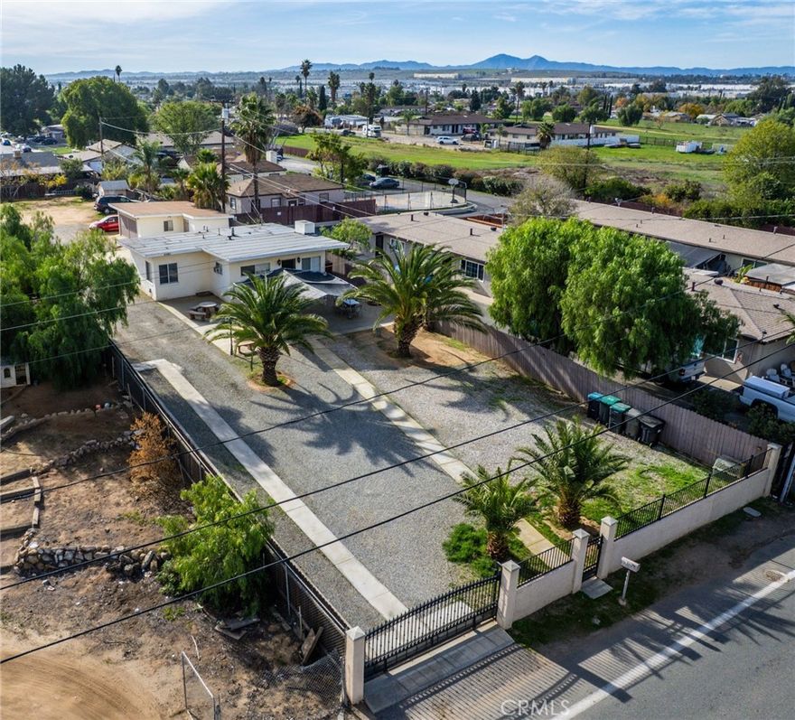 Situated on a generous lot with gated access and ample driveway space, the property offers privacy and room for multiple vehicles, outdoor entertaining, or future possibilities. The main residence (764 living square feet) features two bedrooms and one bathroom. The open floor plan includes a living room, a dining area, a kitchen and a laundry room.  In addition, the property has a detached garage that has been converted into additional living space. The converted garage offers two bedrooms, a living room, a bathroom, and a kitchen area with a stove and sink. Conveniently located near shopping, dining and the freeway. The property also has a view to the iconic "M" on Box Springs Mountain.