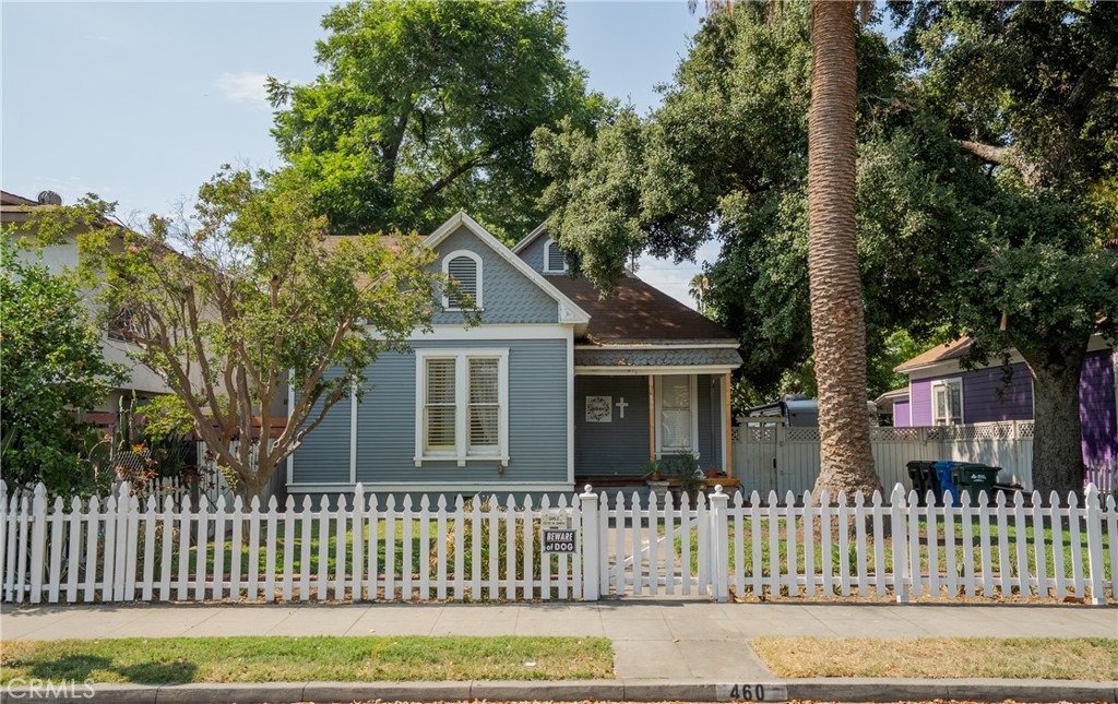 Nestled in the heart of Pomona's highly sought-after Lincoln Park Historic District, this beautifully preserved 1901 Queen Anne Cottage blends historic charm with modern comfort. From the moment you arrive, the white picket fence and inviting front yard set a welcoming tone for this 3-bedroom, 2-bath gem. Step inside to discover high ceilings and rich dark wood flooring that contrasts elegantly with the crisp white finishes throughout. The open-concept living area is both bright and welcoming, centered around a beautifully detailed fireplace with a stately white mantle that adds charm and warmth to the space. The updated kitchen, with its spacious center island, is perfect for casual dining and entertaining, while a formal dining area just off the kitchen adds to the home’s character and functionality. Two of the bedrooms offer generous size and character, while the third bedroom at the rear of the home provides added privacy, an en suite bath, and direct access to the backyard—ideal for guests or a private retreat. Out back, you'll find a versatile custom shed that can serve as a flex space, studio, or storage, along with convenient alley access offering potential for RV or small camper parking. Located just a short stroll from Lincoln Park, this home is a rare opportunity to own a piece of Pomona’s architectural history, thoughtfully updated for modern living. A true blend of timeless elegance and everyday livability!