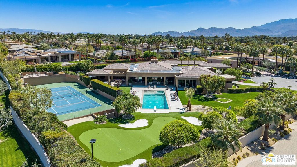 The ultimate hide and reveal retreat strategically perched like a well-earned trophy inside this exclusively gated "lucky seven" residences of Big Sioux. A masterpiece of design and privacy, this private sanctuary is strategically positioned between the iconic Annenberg Sunnyland's estate and Tamarisk Country Club in Rancho Mirage. The expansive single-story layout, encompassing 8,145 sq. ft. residence epitomizes luxury living while its thoughtful design offers an abundance of space and high-end amenities including six bedrooms and nine bathrooms. This Custom-designed residence is well suited for showcasing the finest collections of art, sculpture and automobiles. Meticulously designed for both grand entertaining and intimate living, while providing a stunning backdrop for creating lasting memories. An open-plan design creates a harmonious flow between indoor and outdoor living areas, defining this exceptional residence. The main living space is a showcase of architectural detail, featuring a magnificent, coffered ceiling with soft, ambient lighting. Expansive floor-to-ceiling windows maximize natural light and offer breathtaking panoramic views of the tranquil 1.39-acre estate. This private oasis includes a golf practice area with massive green with 2 hit pads and 3 sand traps, night-lit tennis court with a VIP viewing deck, a play area, and a shimmering pool/spa sundeck framed by dramatic mountain views. A sophisticated contemporary aesthetic defines the home's decor, highlighted by a calming neutral color palette. The gourmet Spectrum kitchen, designed for both culinary artistry and grand entertaining, boasts meticulous detailing, including dual islands, double ovens/cooktops, and a thoughtfully integrated coffee and beverage bar, creating a focal point for family gatherings. The adjacent media and game room offers a versatile space for entertainment and relaxation, further emphasizing the home's seamless blend of style and functionality. An impressive circular drive, featuring a pyramid-topped porte-cochere, welcomes guests with a dazzling approach, transitioning to a covered gallery walkway that leads past manicured sculpture gardens to the grand entry hall and dining room. The dining room, equipped with exceptional built-in service facilities, is enhanced by a dramatic see-through fireplace, creating a captivating focal point for entertaining. Thoughtfully designed directional doors provide the option to discreetly isolate the private bedroom suites wing during larger events, balancing public and private spaces. The great room, a symphony of space and light, serves as the home's central gathering area, featuring a wet bar with seating for six, a game table area, a media lounge with a warm fireplace, and a lit display wall, offering the perfect setting for a grand piano. A haven of tranquility, the delightfully detailed home office overlooks the sculpture garden and double-door entry leads to the dual primary suites, creating a private retreat. These luxurious quarters include an owner's lounge with a kitchenette, a flexible space for a nursery or wellness studio, a secondary laundry, a walk-in wardrobe, and private facilities. The property unfolds into a series of enchanting outdoor living spaces, where a family room with a large-screen television, a built-in barbecue, and a crackling fire pit invite gatherings and quiet moments alike. These spaces offer sweeping panoramic views of the verdant landscape, crafting a picturesque haven for morning coffee or tranquil contemplation. The property features an impressive, oversized four-car tiled garage, complemented by two additional stalls and a motor court. An adjacent service and/or catering entrance provides convenient access, while a deluxe staff suite, complete with a fireplace, offers comfortable accommodation. Abundant storage, additional refrigeration, and a dedicated laundry room ensure efficient household management.
