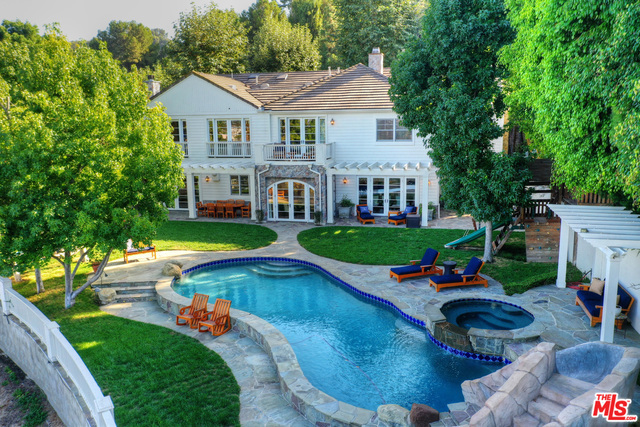 Gorgeous Traditional home in prestigious 24-hour guard gated Mulholland estates. Grand two story light filled entry, large mahogany paneled library/office, formal living room w/fireplace. Dining room, breakfast room, gourmet kitchen with center island and family room w/ fireplace all overlook spacious yard, patio, sparkling pool and city views. Upstairs, three family bedrooms circle a TV/play area. Grand master suite features high ceilings, his and her office spaces and sweeping city views. Impeccable house suited for the most discerning buyer.