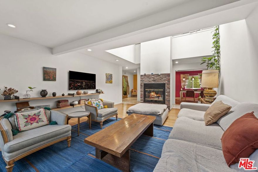 Tucked within a peaceful and highly coveted pocket of Santa Monica, this rare 4-bedroom, 3-bath townhouse lives like a single-family home. One of only two residences in the complex, it offers a lush outdoor patio, privacy, natural light, and the feeling of a detached single-family home. The home's inviting layout revolves around a dramatic two-story living room with soaring ceilings, a central fireplace, and a skylight that floods the space with sunshine. Upstairs, the open circulation around the living area creates an airy, architectural sense of volume. The main level includes a bedroom with its own private terrace, a cheerful dining area with vibrant color accents, and a well-appointed kitchen that opens to the enchanting backyard. This serene and meticulously maintained outdoor space  complete with a lemon tree, garden plantings, and a large dining area  is perfect for entertaining, al fresco dinners, or relaxing under twinkling string lights. Upstairs, the spacious primary suite features abundant light, a walk-in closet, and a recently remodeled bathroom showcasing colorful bohemian-chic tile, double vanity, soaking tub, and separate shower. Two additional bedrooms share a modern bathroom with bold red tile and a generous shower. Warm, welcoming, and full of charm, this home combines modern convenience with creative and eclectic characteroffering multiple private outdoor spaces, natural light from every direction, and the rare feel of a standalone home in the heart of Santa Monica. Located minutes from Water Garden and Colorado Garden Park, walking distance from Erewhon, within proximity to the beach, restaurants, markets, this charming property is truly in one of LA's most iconic coastal neighborhoods.