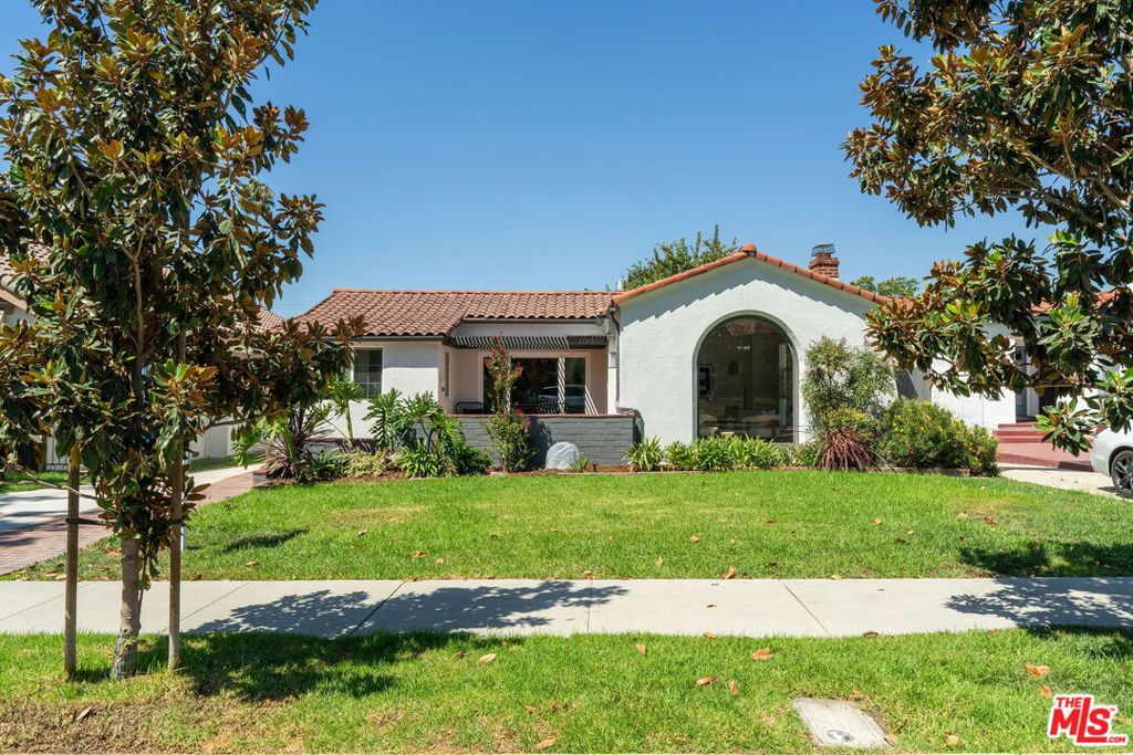 In the heart of historic Rossmoyne, this Spanish-style home is a rare exclusive offering. Every inch has been thoughtfully reimagined with modern design, creating a space that feels both fresh and refined. Graceful archways and a picture window nod to its 1920s roots while showcasing elevated style with high-end finishes. Inside, the living room is anchored by a custom fireplace and mantel that create a striking focal point. A large floor-to-ceiling arched picture window fills the space with abundant natural light. Nine-foot ceilings with soft archways throughout the home turn simple transitions into architectural moments. Wide plank floors and neutral walls add to the home's airy, inviting character. At the heart of the home lies a gourmet chef's kitchen that combines clean lines and warmth. The open-concept floor plan connects the kitchen and dining area, blending simplicity and everyday functionality. Custom oak cabinetry with slab front design, KitchenAid appliances, open shelving, and Dekton quartz countertops are centered around a large island with bar seating, making the space both stylish and practical. The seamless flow creates a natural hub for cooking, gathering, and entertaining. Down the hall, a row of archways leads to three bedrooms, including a primary suite with a spa-like en-suite and a custom walk-in closet. A skylight bathes the hallway with natural light, highlighting the meticulous detail in the design. Both bathrooms have been fully updated with fresh tilework and contemporary finishes that bring comfort to everyday routines. The backyard offers a relaxed resort-like retreat with a raised redwood deck, fire pit, and a shaded "PyeongSang" lounge under a mature tree. A lower concrete patio adds extra space for entertaining, play, or everyday use. Additional improvements include double-pane windows, new HVAC ducting and insulation, new electrical wiring with integrated lighting, copper plumbing, and a tankless water heater. This is a move-in-ready home that combines the coveted location of Rossmoyne with the rare exclusive benefit of a complete modern reimagination.
