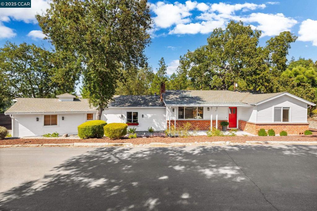 Tucked on a hilltop in Walnut Creek, just minutes from downtown, this single-story retreat combines natural privacy with city convenience. A covered porch welcomes you into an inviting interior where natural light pours through skylights and hardwood floors extend throughout. The living room centers on a fireplace with built-ins, creating a warm and functional focal point. The kitchen features a gas range and dining nook with direct access to the back deck, blending indoor comfort with outdoor flow. The primary suite offers dual closets and an ensuite bath, while two additional bedrooms share a full hall bath. A dedicated laundry room with exterior access adds everyday function. Outdoor living is highlighted by hillside views, raised garden beds, and a spacious deck shaded by mature trees. Excellent location close to BART and commuter routes, with access to highly rated Walnut Creek schools including Parkmead Elementary, Walnut Creek Intermediate, and Las Lomas High.