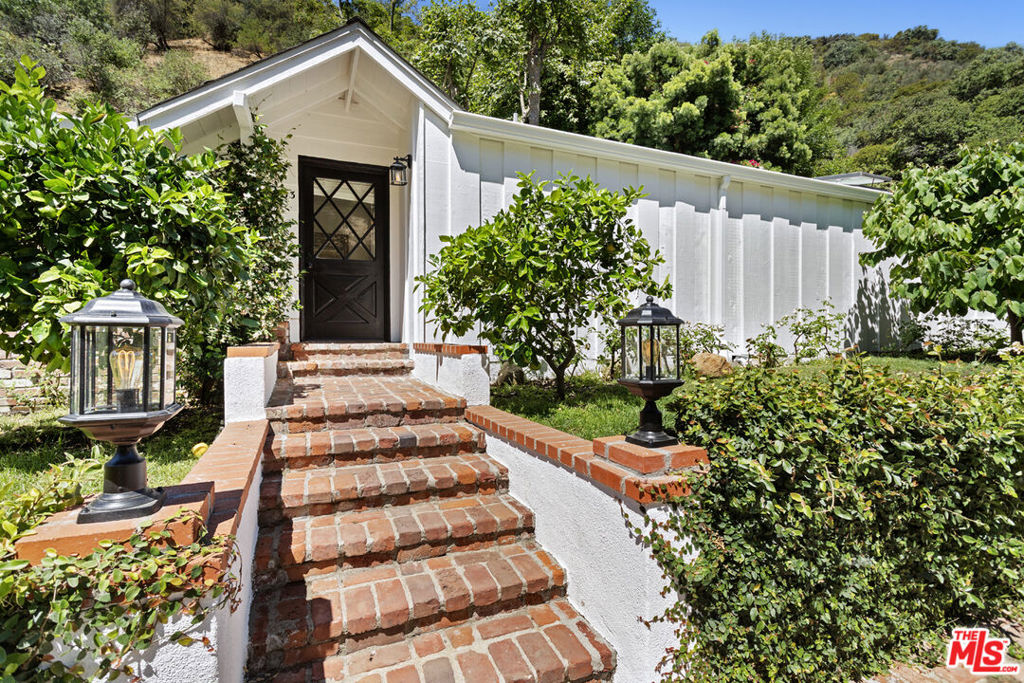 Discover this delightful cottage-style residence nestled in the serene enclave of Mandeville Canyon. Ideally located near two scenic hiking trails, it offers easy access to nature just moments from your door. Offering approximately 1,625 square feet of inviting living space, this beautifully maintained home features three spacious bedrooms and two bathrooms, recently updated with modern touches. Enjoy the cozy fireplace in the light-filled living room, and entertain guests in the dedicated dining area, which seamlessly connects to the home's charming layout and welcoming atmosphere. Natural light pours in through skylights throughout the house, including both bathrooms, enhancing the airy and bright ambiance. Step outside to a serene, enclosed backyard oasis adorned with fruit trees perfect for relaxing or enjoying al fresco dining amidst peaceful surroundings. This enchanting home blends classic cottage charm with thoughtful updates, creating an ideal sanctuary in one of Los Angeles' most sought-after neighborhoods.