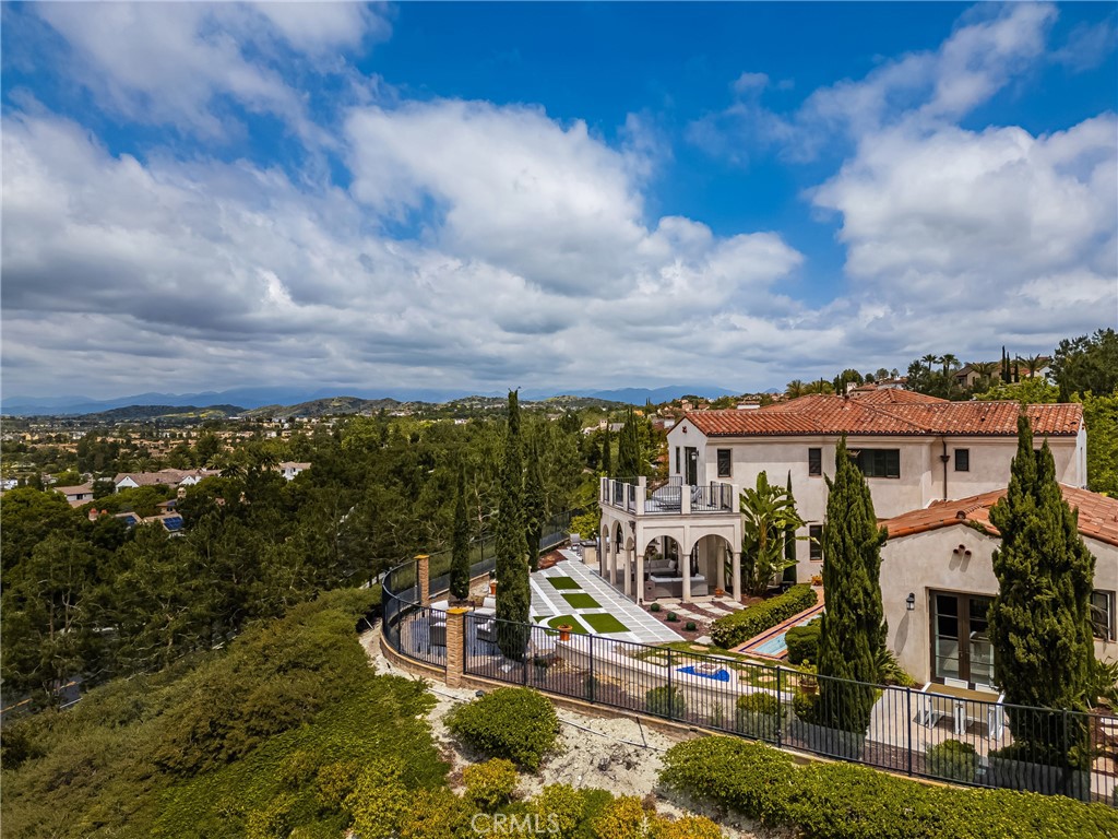 Nestled within the prestigious 24-hour guard-gated community of Covenant Hills in Ladera Ranch, this exquisite custom-built Spanish Villa has been thoughtfully upgraded to reflect modern luxury and sophistication. Boasting 6 bedrooms, 6 bathrooms, and a 3-car garage, this home is ideally situated on a premium VIEW LOT at the end of a quiet cul-de-sac on a single-loaded street. Set on an expansive 11,000+ sq ft lot, it offers sweeping, unobstructed views of city lights and serene rolling hills. The main residence features 5 bedrooms, 4.5 bathrooms, and a 2-car garage, while a separate PRIVATE CASITA includes 1 bedroom, 1.5 bathrooms, its own full kitchen, living and dining areas, laundry room, and 1-car garage with EV charger —perfect for multi-generational living, guests, or rental income. Step into the main home through a formal foyer with soaring ceilings, dramatic Spanish tile, and a grand staircase. The open-concept layout flows into the Great Room, centered around a cozy fireplace. The chef-inspired kitchen features custom European cabinetry, granite countertops, a built-in refrigerator, professional-grade stainless steel appliances, 6-burner cooktop, generous storage, and a charming coffee nook. The oversized island is ideal for entertaining and anchors the space. Accordion doors open to the California Room and lush backyard—perfect for contemporary indoor-outdoor living and entertaining with BREATHTAKING VIEWS. Formal dining and living rooms enhance the home’s elegant design, while an interior courtyard with a tranquil fountain adds serenity. A main-floor guest bedroom with en suite bath offers convenience, and a home office provides a great work-from-home setup. Upstairs, a cozy loft and four bedrooms await, including the LUXURIOUS PRIMARY SUITE with a private balcony, spa-like bath, soaking tub, dual vanities, and two walk-in closets. Additional bedrooms include one with an en suite bath and two that share an upgraded bathroom. The CASITA is a private retreat with its own primary suite, walk-in shower, dual vanities, and French doors opening to a garden with fruit trees and vegetables. The expansive backyard is an entertainer’s dream, with a covered California Room and panoramic views. Residents enjoy resort-style amenities: clubhouse, pools, parks, hiking trails, skate park, and water park. Don’t miss this rare opportunity to own a one-of-a-kind estate in one of Ladera Ranch’s most coveted neighborhoods!