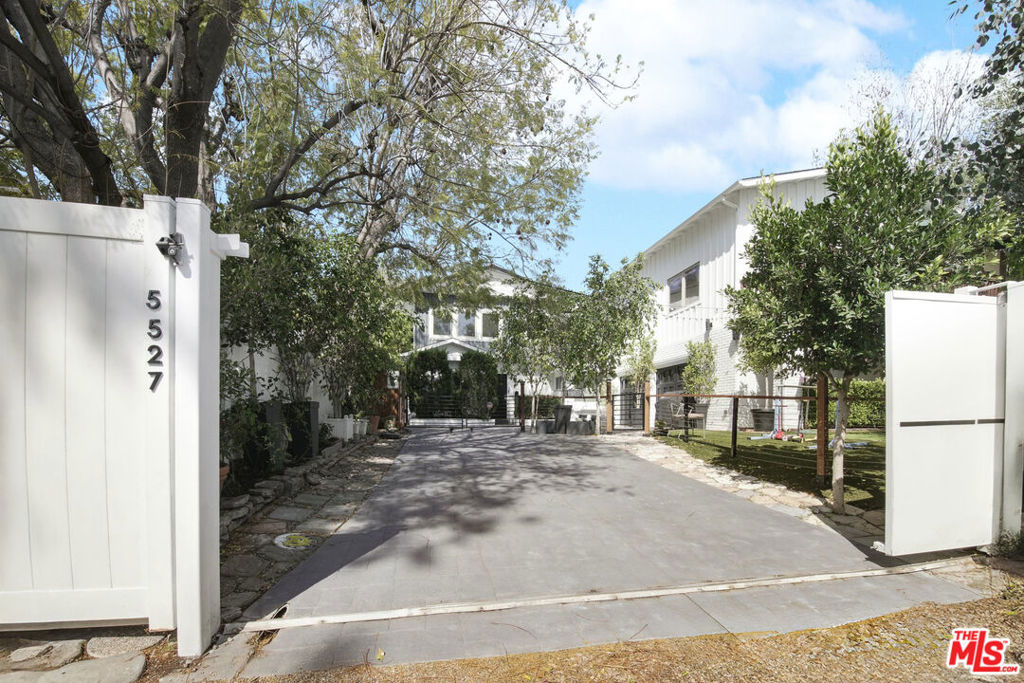 Welcome to 5527 Columbus Avenue, a private and beautifully updated residence nestled in the heart of Sherman Oaks' coveted Magnolia Woods neighborhood. Behind gates and surrounded by mature trees, this thoughtfully designed home blends classic comfort with modern flexibility, offering layered living spaces, refined finishes, and the rare luxury of multi-generational potential.Step inside to an open and airy interior where warm wood floors, crisp white walls, and an abundance of natural light create a grounded yet elevated atmosphere. The formal living room is anchored by a timeless brick fireplace and flanked by large glass sliders that invite in serene views of the backyard. Adjacent, a second lounge with its own fireplace offers a casual space for gathering or unwinding, each room providing its own rhythm within the home's flowing layout.The kitchen is both functional and polished, featuring white cabinetry, granite countertops, stainless steel appliances, a farmhouse sink, and a mosaic backsplash that adds just the right amount of texture. Designed for everyday ease, it sits at the heart of the home with effortless connection to both living areas.On the main level, two well-proportioned bedrooms and a dedicated home office are quietly positioned for comfort and privacy, served by two full bathroomsideal for guests, work-from-home life, or extended family.Upstairs, three additional bedrooms unfold, including two distinctive primary suites. The main retreat feels like a sanctuary with its private balcony, spa-like bathroom, dual vanities, jetted tub, and oversized shower. A second primary offers its own reading or library nook and a beautifully appointed en suite bathperfect for shared living or a private workspace. Each bedroom offers its own character and sense of calm, while a hidden 28' x 8.5' bonus space adds incredible functionality for storage or creative use.Outdoors, the backyard reveals a series of thoughtfully designed momentslush turf underfoot, a saltwater pool with safety enclosure and outdoor shower, a pergola-covered lounge, and a custom-built two-story playhouse with swings, monkey bars, and a climbing wall. A 3-hole putting green and designated dog run complete the setting, balancing play with peace and privacy. At the rear of the property, a separate guest apartment includes a full kitchen, bedroom, bath, laundry, and a generous private deckoffering flexibility for visiting guests, live-in support, or creative studio space. Additional features include 31 solar panels, Nest thermostats, Pella one-touch blinds, a gated motor court, three large storage units, and a full home security system. Pool and yard care, and internet are all included in the lease. Situated in a fantastic central location just moments from the award-winning Kester Elementary/Kester Magnet School - easy and convenience from the front gate and only minutes to Ventura Boulevard's shops and dining. Enjoy close proximity to the Metro Orange Line, nearby parks, scenic bike trails, and effortless access to the Westside. 5527 Columbus Avenue is a rare opportunity to lease a home that truly lives like a private compoundlayered, livable, and ready for its next chapter.