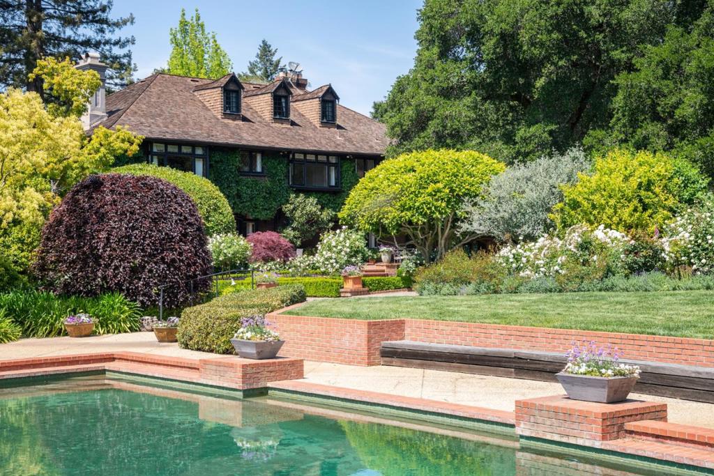 Amazing Western Hill views in the sought after Mountain Home corridor in Central Woodside; this 3.5 acre gated fully fenced estate, offered for the first time in nearly 60 years. Situated at the end of a quiet cul-de-sac, come see this timeless treasure, comprised of a classic two story California Craftsman main home, an adjacent carriage house set up for entertaining, a pool and peaceful pathways through the mostly flat grounds. Ideal for indoor/outdoor entertaining, the main home has large Living and Family rooms with French doors opening out to a spacious entertaining patio framed by mature heritage oaks and world class English Gardens showcasing the spectacular western sunsets. Light-filled kitchen has been recently updated. Upstairs, a spacious primary suite with updated bathroom and home office, near the additional four bedrooms. Unusual privacy and tranquility within close proximity to Town Center shops, restaurants, in close driving distance to Silicon Valley & airports