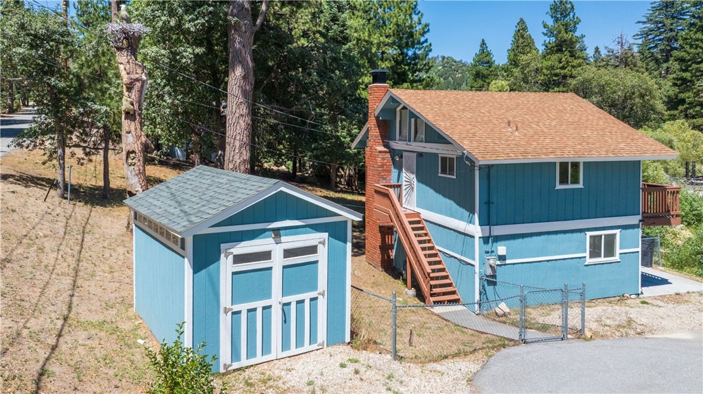 Tucked among the pines in a peaceful setting near Highways 18 and 330, this inviting mountain cabin combines thoughtful updates with classic charm. Featuring a reverse floor plan, the upper level welcomes you with newer flooring, an open-concept kitchen with granite countertops, custom cabinetry, and an abundance of natural light.
Downstairs, you'll find two comfortable bedrooms, each equipped with its own wall heater for cozy mornings and chilly nights. One of the bedrooms includes a convenient an adjoining half bath.
The fully fenced yard backs to a seasonal stream and offers both a deck and a patio—perfect spots to relax and breathe in the fresh mountain air. A matching Tuff shed provides ample storage for your outdoor and recreational gear.
Additional highlights include a dedicated electrical line ready for an EV charger or generator, and a hand-carved totem pole that greets you at the entrance—a unique and welcoming touch to this quiet woodland retreat.