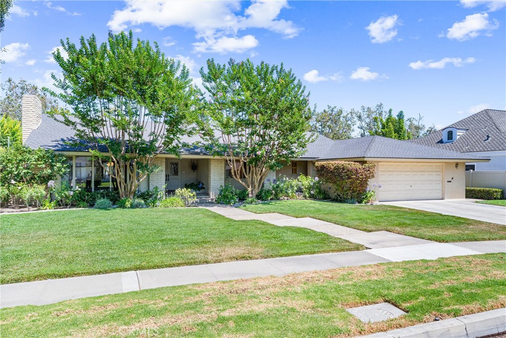 Perfectly located in the highly sought-after West Floral Park neighborhood of Santa Ana, this beautifully maintained Mid-Century Ranch-style home offers timeless charm, modern updates, and incredible curb appeal on one of the area’s most picturesque, tree-lined streets. Situated on an expansive lot, this 4-bedroom, 3-bath residence provides a seamless blend of architectural character and everyday functionality. From the moment you arrive, you’ll notice the inviting presence of mature trees, a wide front lawn, and the classic lines of mid-century design. Inside, the formal living room welcomes you with a stunning fireplace—perfect for cozy winter evenings—and a large front-facing picture window that’s ideal for showcasing your holiday decorations. The separate formal dining room connects gracefully to the spacious kitchen, which features tile countertops, stainless steel appliances, and a cozy breakfast nook perfect for morning coffee and casual meals. Throughout the home, warm engineered hardwood and elegant Terraza tile create a refined, cohesive feel. A generously sized family room—complete with wood-beamed ceilings, a bar, and a brick fireplace with raised hearth—opens to a versatile Arizona room through a sliding glass door, providing the ideal setup for indoor-outdoor entertaining. The private primary suite offers plenty of space and includes its own en-suite bath, while three additional bedrooms are spacious, bright, and thoughtfully positioned. Step outside into your own backyard retreat. A sparkling pool takes center stage, surrounded by mature landscaping including a beautiful magnolia tree, a shaded Arizona room, and ample space for lounging or hosting friends and family. A poolside bathroom and a convenient indoor laundry area with direct yard access add to the home’s smart layout. Natural light pours in from large windows—to maximize daylight—filling the home with warmth and energy throughout the day. Located just minutes from top local attractions including the OC School of the Arts (OCSA), Bowers Museum, Main Place Mall, and vibrant dining options. Easy access to major freeways makes commuting a breeze. This is more than just a home—it’s a piece of Santa Ana history in one of its most cherished neighborhoods. Come and experience the charm, space, and lifestyle that West Floral Park is known for. You’re going to love living here!