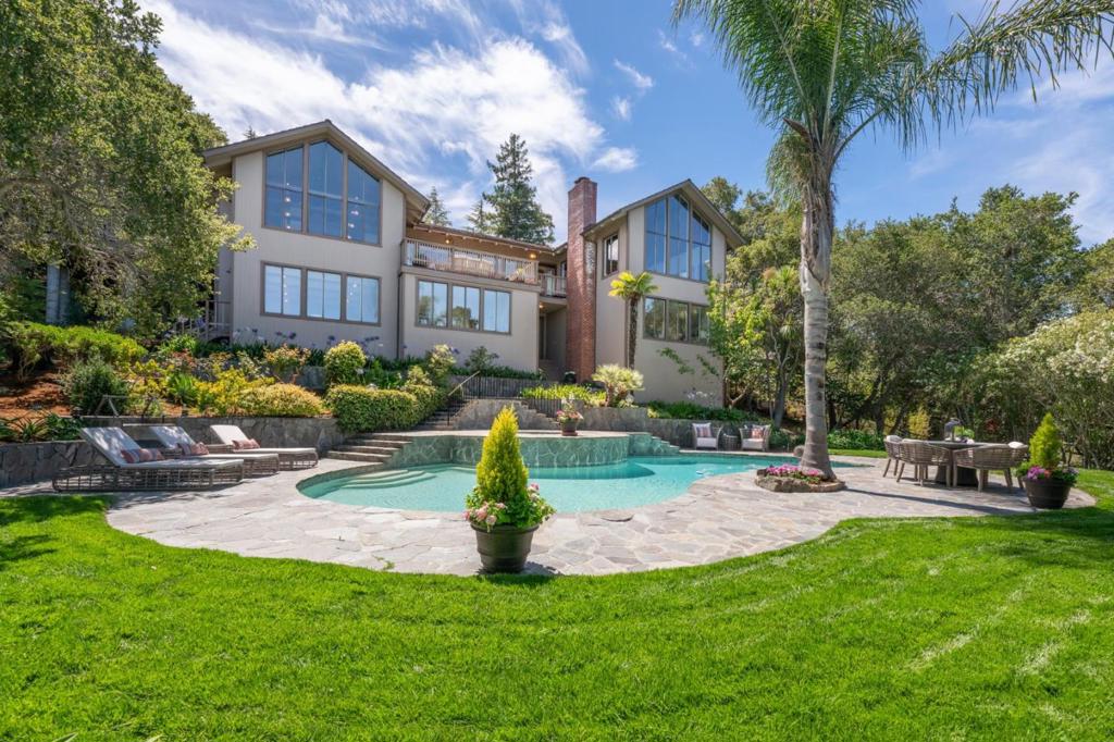 First time on the market ... ever! Mid-century vibes, SF views & a pool in Hillsborough. What is most striking when you walk in are the walls of glass that capture sweeping views of San Francisco and bathe the home in natural light. The main level flows easily between the living room, dining room, and great room/kitchen, opening to terraces perfect for entertaining and dining. The kitchen features a custom-made copper range hood, large island and new oven/stove. There's also a separate catering kitchen plus an office. The primary bedroom has two sitting areas, ensuite bathroom and walk-in closet. There's 3 more bedrooms downstairs plus a family room. The focal point of the tropical-inspired yard is a spectacular palm tree that sways beside a swimming pool and spa surrounded by lawn and privacy. Don't miss the secret wine-room and various pathways, gardens and surprises throughout the property! Hillsborough is also an ideal place to live situated between San Francisco and Silicon Valley with top-rated public and private schools.