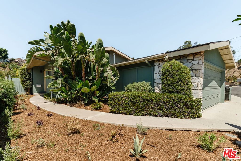 On the market for the first time in almost 40 years, this enchanting ranch-style retreat is sited in the breezy hills above Eagle Rock on a quiet cul-de-sac. Thoughtfully refreshed, the home blends midcentury character with modern ease, offering a rare balance of charm and comfort. A mosaic-set fieldstone entry and a newly landscaped front garden of native blooms, vibrant bougainvillea, and a stately Bird of Paradise create a refined welcome that feels quintessentially California. Step inside to an airy, open layout where natural light pours through a picture window, framing verdant views. A corner brick fireplace anchors the living room, wrapping warmth around gatherings large and small. The kitchen nods playfully to the past with vintage terra cotta tile counters, paired with updated appliances and a casual breakfast bar. Flowing effortlessly to the dining room, sliding glass doors invite you out to the patio; setting the perfect stage for golden-hour dinners under the stars. The serene primary suite, with its en-suite bath and direct access to the lush, grassy backyard, feels like a private haven. Two additional bedrooms and a generous hall bath with dual vanity and sage marmoleum flooring complete the thoughtful floor plan. The backyard unfolds as a verdant sanctuary bordered by fresh landscaping and mature plantings. Multiple patios create natural gathering spaces, offering endless possibilities for entertaining. Fully enclosed and private, it's an idyllic extension of the home's living space. The attached two-car garage and wide driveway add both ease and privacy. All just moments from Eagle Rock favorites including Vidiots, Creature's Plants & Coffee, Capri Club, Walt's Bar, Occidental College, and more.