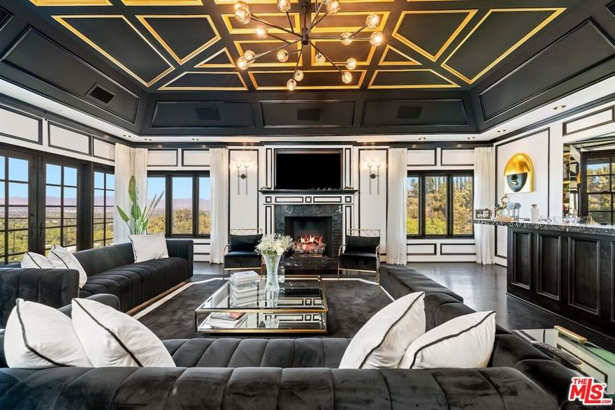 Experience everyday luxury living in this gated French Manor Estate, nestled in one of the most coveted neighborhoods of Encino Hills South of the Blvd. This exceptional residence captures sweeping city-light views and spans over 11,000 square feet of exquisite living space, featuring six bedrooms and eight bathrooms. Completely remodeled, the home blends elevated design with meticulously curated upgrades for comfort, style, and effortless entertaining. Upon arrival, guests are welcomed through a spacious courtyard into a grand entry filled with natural light and soaring ceilings. The great room showcases custom built-ins and coffered ceilings, while the living room's exposed beams create a warm, sophisticated ambiance. The private formal dining room, framed by expansive French windows, seamlessly connects to a butler's kitchen for ease of service. The gourmet kitchen is a chef's dream, appointed with top-tier appliances, a generous island, and a farmhouse sink overlooking tranquil city views. Upstairs, the expansive primary suite serves as a private sanctuary with a spa inspired bathroom featuring an oversized jet shower, double vanities, a fireplace, a large walk-in closet, and a private terrace framing the spectacular views. Three additional en-suite bedrooms complete the top level. Descending to the third level reveals an entertainer's haven with a state-of-the-art theater, an elegant billiards room with terrace access, a sauna, a library, and a climate controlled wine cellar. The outdoor spaces are equally impressive, featuring a sparkling pool, fireplace, basketball court, and pool house perfect for year-round gatherings. This is a residence of unmatched caliber that must be experienced in person to be truly appreciated. Schedule a private showing today and witness its beauty firsthand.