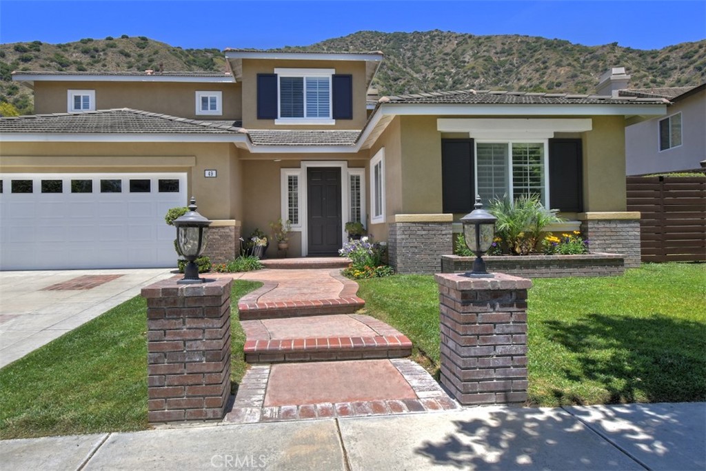 Discover tranquility and comfort in this stunning 4-bedroom home nestled in the prestigious, guard-gated Mountain Cove community! Located toward the back of the neighborhood, this residence offers exceptional privacy while surrounded by nature's beauty. This thoughtfully designed home boasts dramatic 40-foot cathedral ceilings, a spacious and open layout, the convenience of a downstairs bedroom with an adjacent full bathroom, and an oversized backyard with no rear neighbors. The large and remodeled master suite features two spacious walk-in closets, dual sinks, sunken tub and vanity table. The other two upstairs bedrooms are good sized with ample closet space. All bedrooms feature ceiling fans for year-round comfort. Abundant natural light flows through the windows, enhanced by high-end plantation shutters. Brand new luxury vinyl flooring, stunning quartz countertops, a new farmhouse sink in the kitchen and a brand new refrigerator. Remodeled bathrooms, fresh interior paint, and striking modern chandelier in the dining area. Dual-zone HVAC provides customized comfort for both upstairs and downstairs. The outdoor paradise truly sets this property apart with its larger-than-average lot featuring no rear neighbors for ultimate privacy. The covered patio with electrical hookups seamlessly connects to the built-in barbecue area, creating an entertainer's dream. Natural wildflower gardens add seasonal beauty, while new side gates on both sides provide convenient access and privacy. Daily wildlife visitors including deer, squirrels, blue jays, yellow orioles, and gray foxes make this backyard feel like a nature preserve. The spacious 3-car garage offers potential for conversion to an ADU, workspace, or recreation room, adding versatility to the property. Located in the desirable northern part of Azusa, residents enjoy convenient access to downtown Azusa and nearby Costco, while the community clubhouse, pool, and jacuzzi provide resort-style amenities. Regular family events including community luaus foster a friendly, established neighborhood atmosphere. The exclusive community features the San Gabriel River running through it and provides direct access to walking trails, making it perfect for nature enthusiasts who appreciate easy access to the Los Angeles National Forest. This is your personal retreat where modern luxury meets natural serenity in Mountain Cove's guard-gated sanctuary. Welcome to your little piece of heaven!