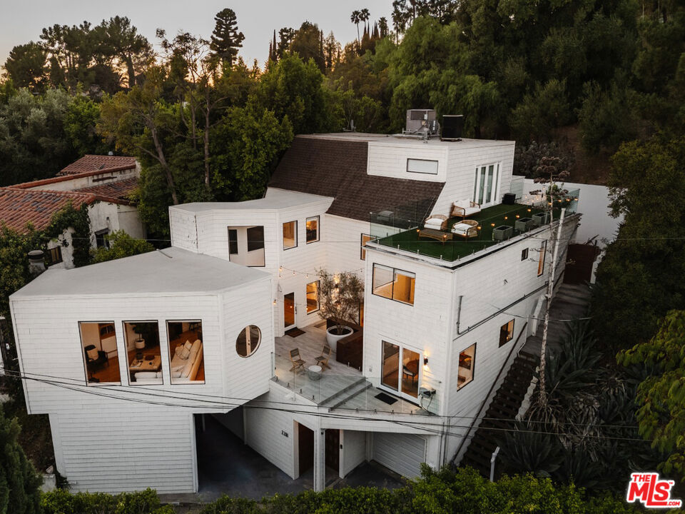 Designed by renowned architect Tony Ngai, AIA, 2261 Vasanta Way is a beautifully updated architectural retreat nestled in the beloved Beachwood Canyon neighborhood of the Hollywood Hills. This thoughtfully designed home offers a blend of modern luxury and coveted Southern California indoor/outdoor living with decks located on each floor. Enjoy panoramic views from the rooftop, spanning from the iconic Griffith Observatory to downtown Los Angeles. Inside, the sleek kitchen features high-end Viking and Sub-Zero appliances, extensive cabinetry, and stone counters, complemented by a breakfast nook. Entertain guests in the formal dining room with its built-in bar and drink refrigerator, or relax in the spacious living room with a fireplace. At day's end, escape to the expansive primary suite, which boasts 30-foot ceilings, French doors leading to a private patio, and direct access to a versatile loft space perfect for a home office or gym. The spa-like primary bath includes a soaking tub, glass shower, dual sinks, LED mirror, and porcelain counters. Additional finishes and features include well-appointed guest rooms, hardwood floors, large windows that showcase the hillside surroundings, soaring ceilings, custom electric shades, designer light fixtures, and a 240v outlet in the garage for EV car charging. Enjoy the perfect balance of seclusion and accessibility, with scenic hiking trails, Lake Hollywood, the Hollywood Sign, and a variety of local restaurants, shops, and entertainment options just moments away. The property can be offered unfurnished or furnished, please inquire for more details.