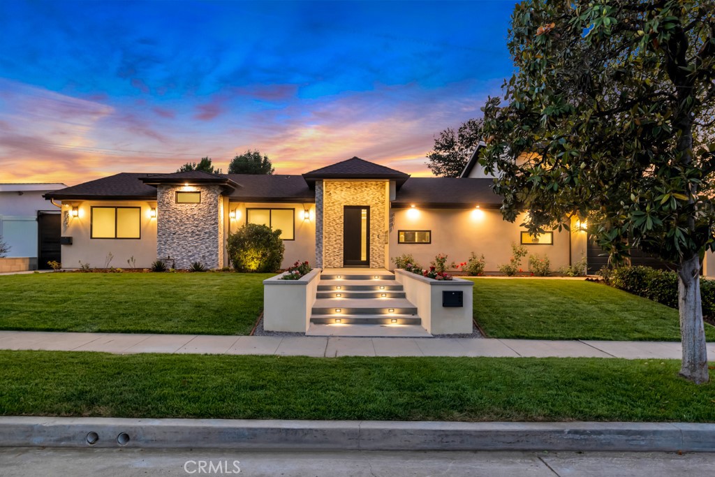 Welcome to this stunningly reimagined contemporary residence that blends high-end finishes with effortless functionality, nestled in a serene neighborhood surrounded by mature trees and lush landscaping. This primarily single-story masterpiece delivers luxury living across every square foot, thoughtfully crafted with exceptional attention to detail. This fully remodeled home features over 3,800 total square feet of generous living space, with 5 bedrooms and 6 bathrooms, which includes a 2 story guest quarters. The heart of the home boasts a striking open-concept gourmet kitchen featuring custom flat-panel cabinetry, professional-grade Thermador stainless steel appliances, dual built-in ovens, and a 60-inch refrigerator/freezer. The oversized waterfall island with quartz countertops, sleek pendant lighting, and high-end stainless-steel sink becomes the centerpiece for entertainment and family gatherings. A seamless flow from the kitchen into the spacious great room and dining area, all bathed in natural light from the oversized sliding glass doors. High ceilings with recessed LED lighting enhance the airy ambiance, while wide-plank white oak hardwood flooring adds warmth and elegance throughout. Minimalist fixtures, matte finishes, with an addition of smart-home living, and custom wood cabinetry throughout blend modern sophistication with subtle luxury. A built-in media wall with surround sound speaker systems anchors the living area, offering both functionality and aesthetic appeal. Step outside to your private resort-style backyard, where lush artificial turf and clean-lined concrete pavers create a polished, low-maintenance landscape. The sparkling pool and integrated spa offer a perfect place to unwind or entertain, complemented by a custom patio lounge area ideal for al fresco dining and summer evenings under the stars. Large sliding doors connect the indoor and outdoor spaces, creating a true California indoor-outdoor living experience. Now out to the front of the home we have a modern façade that is framed by elegant stonework, clean lines, and a dramatic entryway with LED step lighting leading to a bold front door. Elevated privacy walls and fresh landscaping give this home an impressive street presence and a secluded feeling.