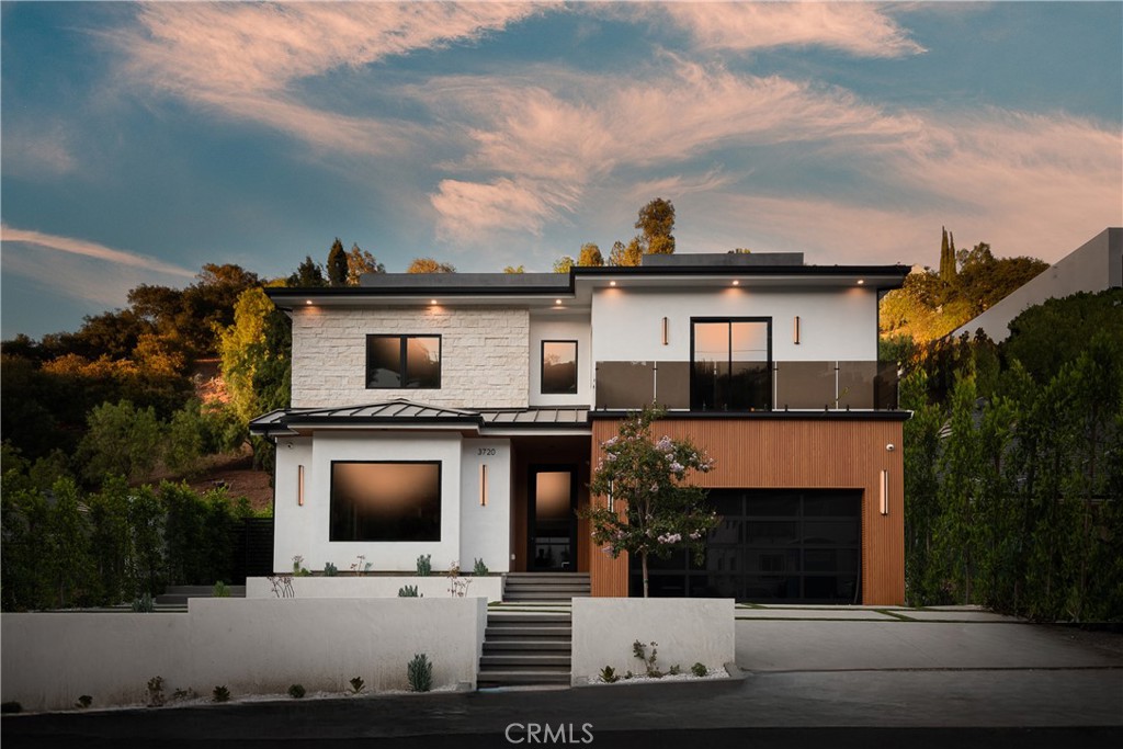 Welcome to 3720 Goodland Ave, a striking architectural estate tucked south of Ventura Boulevard in the heart of Studio City. Completed in 2025, this brand-new modern masterpiece delivers a flawless fusion of bold design, custom craftsmanship, and luxurious amenities—just moments from Erewhon, Harvard-Westlake, and the area’s premier shops and restaurants. At the top of Goodland Ave is a trailhead that connects to the Fryman Canyon hiking loop via a scenic hike.
Sited on a 13,682 sq ft lot, the 6,235 sq ft residence boasts 6 spacious bedrooms and 6.5 bathrooms, thoughtfully designed with high-end finishes and functional elegance. The exterior impresses with warm wood accents, crisp architectural lines, and commanding curb appeal.
Inside, soaring ceilings, oversized picture windows, and seamless indoor-outdoor transitions define the home’s open layout. Rich white oak hardwood flooring, smooth Venetian plaster walls, and extensive custom woodwork elevate every detail. At the heart of the home, the chef’s kitchen features dual center islands, premium appliances, and bespoke white oak cabinetry—perfect for culinary creativity and entertaining alike.
A sculptural staircase anchors the flow between expansive living and dining spaces, designed for both intimate gatherings and grand-scale entertaining.
The primary suite is a luxurious retreat, offering a private balcony overlooking the pool, a spa-inspired bath with soaking tub and dual rain showers, and a massive custom walk-in closet. All secondary bedrooms are en-suite, each with generous proportions and refined finishes.
The outdoor living space is a private oasis—complete with a covered deck, sparkling pool, custom built-in grill, and beautifully manicured landscaping. A detached guest house with a full bathroom offers versatile space for visitors, a home gym, studio, or office.
Located within the Dixie Canyon Elementary School district, this property is crowned by a spectacular rooftop deck spanning over 1,700 sq ft—featuring a custom outdoor kitchen, multiple lounge areas, and sweeping views of the Valley and city skyline. Whether relaxing or entertaining, this rooftop is the ultimate escape.
