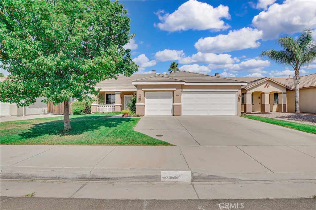 This single story Menifee pool home built in 2003, offers 2107 square feet of living space with four bedrooms, two and a half bathrooms, and a spacious three car converted garage, situated on a 7405 sqft lot. The single car portion of the garage has been thoughtfully converted into a den or additional room with a half bath. Upon arrival, the property captivates with its impressive curb appeal featuring lush green grass, a mature shade tree and a charming front porch with a sitting area. Inside, the formal living and dining rooms offer a welcoming atmosphere, featuring a blend of wood and tile flooring that flows throughout the home. An inviting color palette and natural light enhance the open, airy feel of the space. Just to the right of the entry, you will find a den featuring carpet and a large window. This area connects directly to the converted single car portion of the garage, complete with its own convenient half bath, perfect for a home office, guest space, or playroom. A hallway leads to a full bathroom complete with a shower tub combo, a dual sink vanity and tile flooring. Also down the hallway is the master bedroom and two additional bedrooms, each featuring carpeting, ceiling fans, ample closet space, and windows. The Primary bedroom boasting carpet flooring, multiple windows and a ceiling fan. The private bathroom offers tile flooring, a dual sink vanity, walk-in shower, soaking tub and a walk in closet. Across the hall is a convenient laundry room equipped with built in cabinets and garage access.The living room, featuring tile flooring, a wood burning fire place, media nook and a large window that flood the space with natural light. The bright and spacious kitchen showcases tile countertops, large pantry, and stainless steel appliances including a 5 burner gas cooktop and oven, microwave, and dishwasher. It offers an abundance of cabinetry for ample storage, and a center island featuring cabinets for added storage and bar seating for three. The dining area has a sliding glass door that floods the room with natural light and grants backyard access. Head out to the spacious backyard, perfect for entertaining under the covered patio and relaxing in the large custom in ground pool.This property features two covered patio areas, while mini palm trees, lush green grass, and well maintained landscaping create a peaceful atmosphere. A storage shed adds extra convenience and functionality. Conveniently located near major highways and shopping centers
