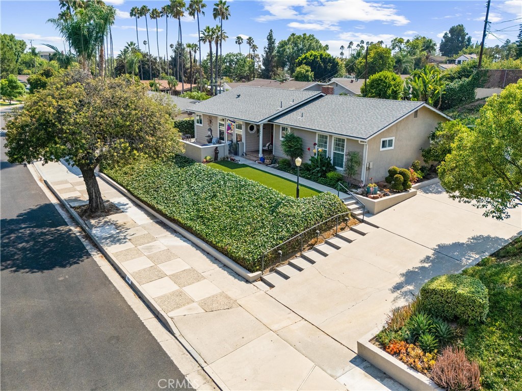 Every once in a while, a truly special home comes to market, this is that moment. Perfectly situated in the highly sought-after Golden Hills neighborhood of Fullerton, this stunning single-story Mid-Century gem combines timeless charm with modern upgrades. Set on an elevated lot on a beautiful street, the home offers a sense of openness and space that enhances its curb appeal. The inviting front patio is the perfect spot to relax with friends, enjoy a beverage, and take in the neighborhood views. Step through the bold red front door and you’re greeted by a light-filled entry that immediately feels warm, welcoming, and beautifully designed. The reimagined kitchen is beyond a showstopper, featuring high-end appliances, a custom tiered island, elegant cabinetry, and designer countertops. Whether preparing a meal, entertaining guests, or simply enjoying your morning coffee while watching the sunrise, this space was made to inspire. The adjacent living and dining rooms boast original hardwood floors, a charming corner fireplace, and seamless flow for both entertaining and everyday living. Just steps down, a den with paver flooring opens to the resort-style backyard through double doors. The spacious primary suite is bathed in natural light with windows to the east and side yard, and its updated en-suite bath includes a walk-in shower and stylish tile finishes. On the other side of the hallway there are two additional bedrooms (one currently used as an office/library) and a gorgeous remodeled full bath with soothing white and blue hues evoking the feeling of a day at the beach or the spa. The backyard truly is your private retreat complete with a sparkling pool, BBQ station, multiple lounge and dining areas, and lush landscaping which includes flowering citrus trees. Vacation at home year-round in this outdoor paradise! A three-vehicle garage and extended driveway add to the home’s convenience and appeal. This Golden Hills beauty truly has it all, — style, comfort, and an unbeatable location with so much that Fullerton has to offer nearby. Nature Trails leading you to Laguna Lake, Hillcrest Park, the steps at Lions Field, Cultural events at the Muckenthaler and Downtown Fullerton dining plus so much more. Added bonuses of an electric car charger, a new roof, and brand new 18 solar panels too! Clearly a home that has been truly loved, enjoyed and cherished by its current owners, now available for you! Don’t miss the chance to make this remarkable home yours!