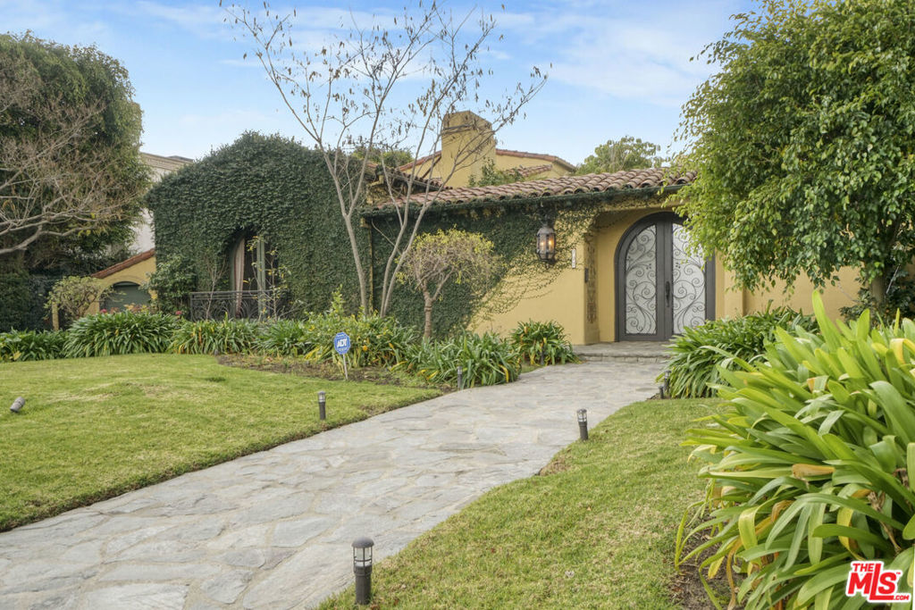 This exquisitely restored 1920s Spanish retreat is located in the prestigious Flats of Beverly Hills, seamlessly blending timeless elegance with modern luxury. Gleaming hardwood floors and high ceilings, many with intricate beamed designs, flow throughout the home, highlighting its authentic character. The stunning formal living room showcases a soaring, hand-painted beamed ceiling and an elegant fireplace adorned with a hand-painted crest above. An equally impressive formal dining room boasts an antique, intricately paneled, and hand-painted ceiling, the perfect setting for intimate dinners or grand entertaining. At the heart of the home is a gourmet chef's kitchen with a center island, separate breakfast bar, and breakfast room. An adjoining built-in bar and a spacious family room with fireplace create an inviting space for entertaining or relaxing. The light-filled primary suite is a serene retreat, with walls of French doors opening to a private balcony. The luxurious primary bath features dual vanities, a soaking tub, and a large shower with dual showerheads. Banks of French doors open the interiors to the outdoors, where a custom barbecue area, arbor-covered terrace with a built-in lounge, dry sauna, and full bath await. A tranquil, tiled-bottom pool and spa are surrounded by lush landscaping, offering an exceptional space for both entertaining and quiet retreat. Elegant custom details make this serene Beverly Hills gem a truly exceptional offering.