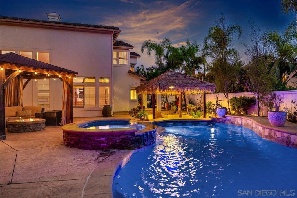 Your private resort paradise awaits! Located in the exclusive neighborhood of Oceanside, The Missions at Ivey Ranch, & set on nearly 1/3 of an acre in a cut de sac, this stunning residence offers a truly exceptional backyard! Unwind & relax in the glowing west facing pebble tec pool, jacuzzi, slide & cascading waterfalls or entertain under the palapa, by the firepit or the beautiful zen garden! With a solar system, convenient first-floor bedroom, soaring ceilings, a sweeping staircase, and a chef’s kitchen perfect for gatherings, this home has everything you’ve been looking for. It’s warm, spacious, and full of character—don’t miss your chance to see it! Excellent schools at a walkable distance. In the heart of The Missions, one of Oceanside’s most distinguished neighborhoods, awaits a home where every day feels like a getaway. Bathed in golden westerly light, the backyard is a private resort in its own right—anchored by a sparkling Pebble Tec pool, cascading waterfall, and a thrilling 20-foot slide that invites joy at every turn. Unwind in the spa beneath the stars, sip drinks at the palapa bar with underwater seating, or simply lose yourself in the tranquil beauty of the garden, where apple trees and desert drought tolerant plants offer a quiet connection to nature. Set on 0.26 acre, this home equipped with owned solar, offers space to breathe—both inside and out. Step through the front door and you're greeted by soaring ceilings, generous living areas, and a well-designed kitchen that opens to a wonderful covered patio and charming family room with its elegant fireplace place. With four bedrooms, including a convenient first-floor suite with a full bath, and a large bonus room that adapts to your lifestyle, the layout is as versatile as it is inviting. Upstairs, the expansive primary suite surprises with a spacious walk-in closet discreetly tucked behind mirrored sliding doors. This is not just a house—it’s a place where memories are made, where the sunlight lingers just a little longer, and where the rhythm of everyday life slows to something richer, more joyful. Come discover the magic for yourself!