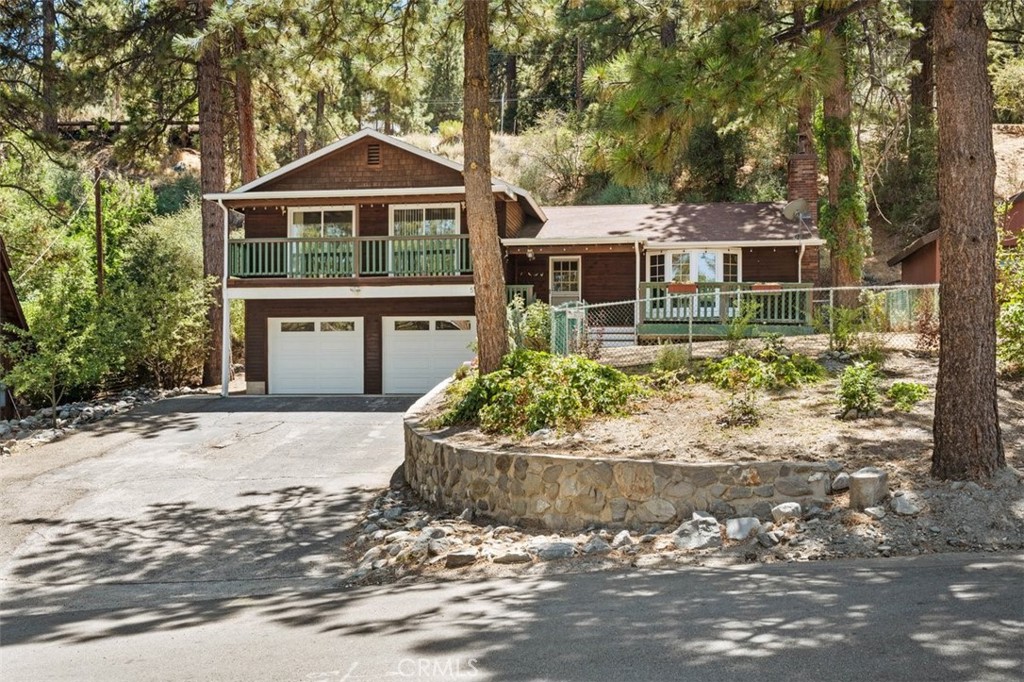 Lovely 3 bedroom, 2 bath home on a tranquil and desirable street with commute access via Lone Pine Canyon or Hiway 2. Entry to home is from a large front porch into the living room that has beautiful shuttered bay windows with window seating and a beautiful Iron Strike Insert in the fireplace. Iron Strike is known for their warmth, beauty and efficiency. Each room has ceiling fans and recessed lighting. The home also has direct entry through a large double door garage, with stairs leading into the home. Garage is spacious so plenty of storage space for all those holiday decoration that is fun to use once you are living in a four season community. Kitchen is large and is attached to the dining area. Kitchen has been updated with a newer stove, microwave, and dishwasher. Laundry area is a separate room off the kitchen with its own utility sink. Back deck is as private as it gets. No neighbors peering down on you as the home backs right into the mountain. The private family quarters up a few stairs has the master suite with private bathroom, and direct access to the deck. THINK SPA TIME BEFORE BEDTIME! The other 2 bedrooms have large closets and each has its own private balcony. This home has newer carpet throughout, and 2024 new septic system and a newer water softener system and just added a new irrigation system just to make sure the apple trees flourish.