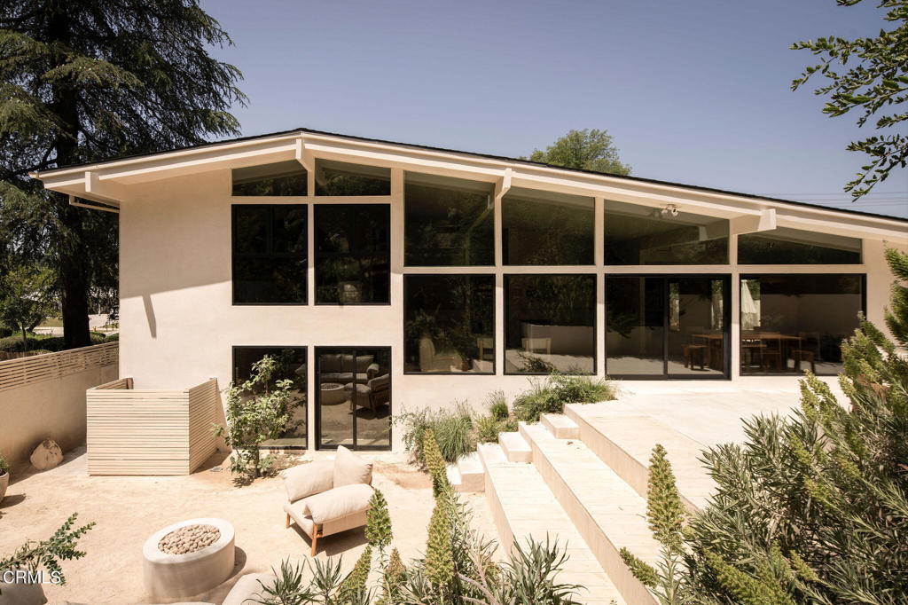 This meticulously renovated midcentury home blends contemporary design with European elegance. Situated on a serene, tree-lined street, the 3-bed, 2-bath residence features natural materials, cascading windows, and lush landscaped views. The main living space connects to a newly landscaped area with a pool, spa, vegetable garden, and custom fire pit by ORCA. High-end finishes include Venetian plaster walls, white oak flooring, custom oak doors with Emtek hardware, and bronze faucets. The living room has floor-to-ceiling windows for abundant natural light. The gourmet kitchen boasts a custom-imported Fenix design with ORCA clay paver flooring, Fleetwood doors, scratch and heat-resistant countertops, and Gaggenau appliances. The dining room opens to an outdoor patio. Upstairs, two bedrooms share a luxurious bathroom with Inbani marble sinks and By COCOON fixtures, while the primary bedroom on the bottom floor opens to a private outdoor space with a concrete fire pit. Additional upgrades include a new roof, HVAC, Fleetwood windows, tankless water heater, and updated electrical and plumbing. The fully gated home has a resort-style pool and spa, and a garden with vegetable planters and various fruit trees. Located near Woodland Hills, Calabasas, Topanga Canyon, and top schools like Calabash Charter Academy and Rainbow Planet Montessori, this home offers a tranquil retreat with modern amenities.