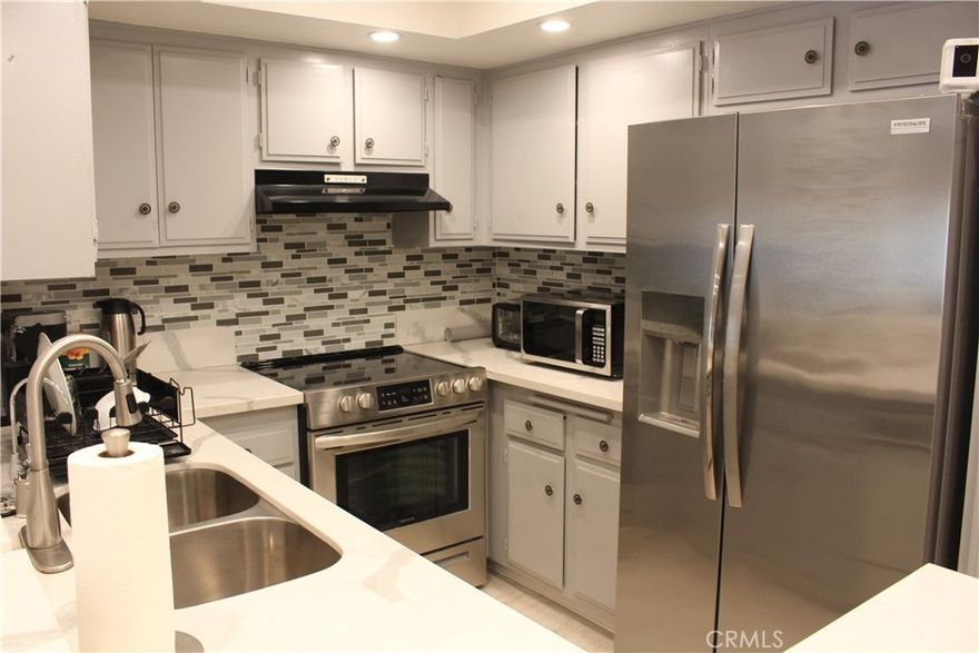 Unit E11  NO ONE ABOVE OR BELOW AND THIS UNIT HAS A BACK YARD!!!    This charming Condo is one of the few in the community that offers a private backyard —perfect for outdoor relaxation or entertaining. Step into the spacious family room featuring tile flooring, crown molding, baseboards, recessed lighting, and direct access to the backyard through a sliding glass door.  The remodeled kitchen offers a modern design with a breakfast counter and space for a dining table, stylish backsplash, and newer appliances. Both bedrooms are generously sized with ample closet space. One of the bedrooms includes a convenient Murphy bed and enjoys abundant natural light.  The subterranean parking is very close to the unit, there are two spots and some storage space.