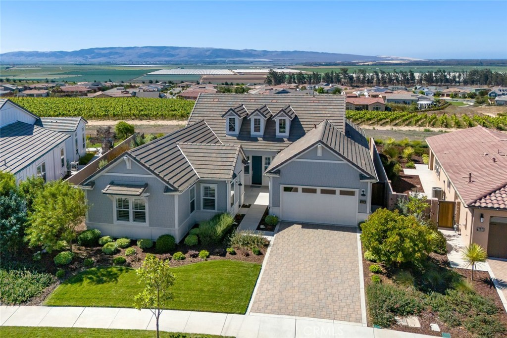Here’s your opportunity to own a beautiful coastal exterior Ventana home, located on a super premium lot with a panoramic view of vineyards and hills to the south, plus the ocean and dunes to the west - it’s simply breathtaking! This gorgeous solar home offers 2,517 sq. ft. of prime living space with 3 bedrooms, 3.5 baths, (which includes a guest wing with private entrance), plus a den. Step inside and discover a stunning open-concept kitchen/great room/dining area with natural plank engineered wood floors and incredible views, which surround the outdoor space, lending itself to seamless indoor/outdoor living. You’ll love the centrally-located culinary kitchen with soft ivory colored quartz countertops and island combined with rich, upgraded espresso Shaker-style cabinetry - it’s an inviting combo that continues throughout. Top it off with the latest flush-mounted GE Profile stainless appliances, including a 5-burner gas cooktop, white tile backsplash, brushed nickel fixtures, and a spacious walk-in pantry - large parties or small gatherings, this space can handle it with ease. Outside, the landscaping is impeccable with covered patio, meandering pathways, low-maintenance plants and shrubs, artificial turf and ambient lighting - all with incredible views in every direction. The versatility of this home continues when you host family and friends for overnight stays, you’ll have plenty of room with a large bedroom and full bath next door, plus a guest suite, (living room, bedroom and full bathroom) with its own private entrance. Once your guests are comfortably tucked away, head to your primary suite, a personal retreat, featuring a spacious bedroom with an inviting window seat and a luxurious spa-like bath with tile floors, beautiful tile shower with seamless glass enclosure, Roman tub, dual sinks, walk-in closet and linen storage - it’s a slice of paradise you’ll enjoy every day! Taking care of business is also a breeze with the oversized SmartSpace and laundry with desk, storage cabinets, countertops and sink - it’s the perfect spot to catch up on email or jump on a zoom call. Additionally, there’s a den with French door enclosure, powder room, 2-car garage with showroom epoxy floors, A/C and plantation shutters where needed. You’ll never want to leave this magnificent home, but when you do, you’ll be amazed at all the activities Trilogy life has to offer.