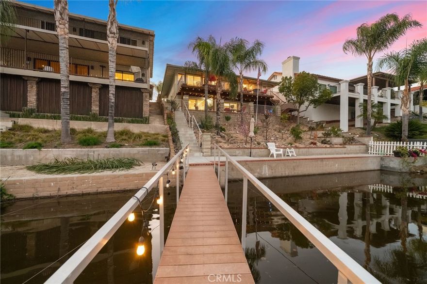 WATERFRONT Upgraded Home on the East Bay with private dock that has been freshly painted outside including deck and railings. This home features 3 bedrooms, 3 bathrooms, over 2000 square feet, 2 fireplaces, and paid solar. The open-concept layout is bathed in natural light, with wide sliding glass doors that bring in the light and open to a generous sized deck - perfect for watching the sunrise in the morning overlooking the water. The remodeled kitchen is  light and bright equipped with high-end appliances, sleek quartz countertops, and a seamless connection to the dining area. A wood-burning fireplace, recently refreshed, adds cozy charm to the living room. The main-level primary suite is a peaceful escape, complete with private deck access, dual closets, and its own dedicated A/C unit. The luxurious attached bathroom features a freestanding clawfoot tub, dual quartz vanity, and a newly tiled walk-in shower - creating a true spa-like atmosphere. An additional bedroom and bath on the main level perfect for additional living or to create an home office. Downstairs provides a private living space ideal for guests or multi-generational living. It includes a large bedroom, a second fireplace, a beautifully remodeled bathroom, and direct walk-out access to the patio, lake, and dock. A gated and enclosed front courtyard and charming pergola offers an additional sitting area. It's a short walk to the lake filled with fruit trees including Donut Peach, Fruit Cocktail, and Nectarine. A private dock with lift -  your personal launchpad for boating, paddle-boarding, or simply enjoying the lakefront serenity. Energy-efficient upgrades include fully owned solar panels, a tankless water heater, and a whole-house fan. The spacious two-car garage with shelving and additional parking for your trailer add practicality to the inviting curb appeal. This home has everything you need to enjoy waterfront living in Canyon Lake. Home is move in ready!