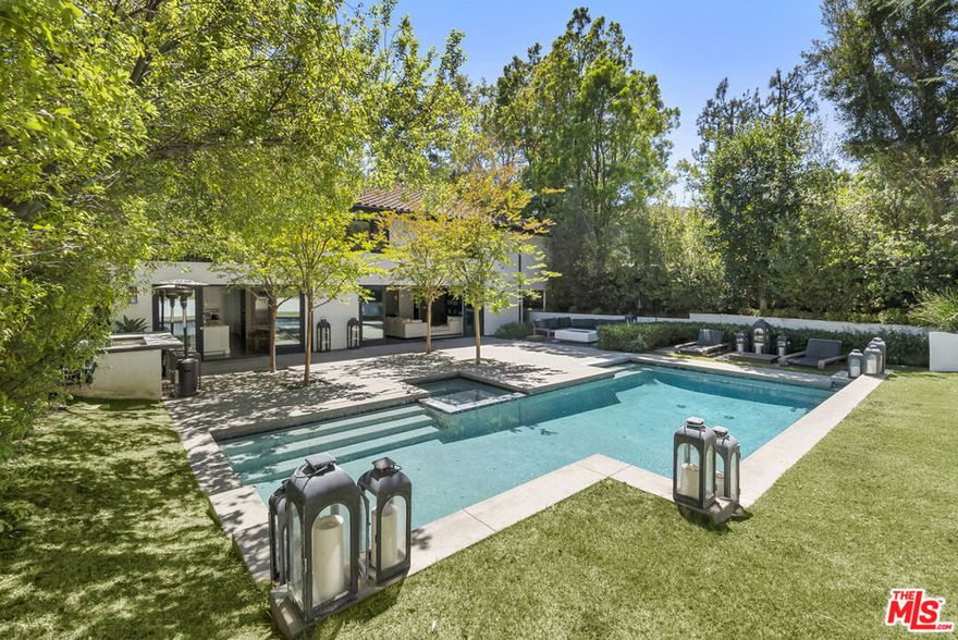 Move in ready, designer family home in one of the most sought after neighborhoods in the hills just north of the Beverly Hills Hotel. Set on a coveted flat street lined with sidewalks, this residence offers access to private tennis courts and 24 hour security patrol in a young and vibrant family community. This modernized traditional home features an open layout where the eat-in chef's kitchen with Calcutta marble, steel shelving, and top-tier appliances flows seamlessly into the living and dining areas.  Walls of glass slide open to the private backyard, creating effortless indoor outdoor living. The family room doubles as a full media lounge with piano and wet bar, while the outdoor kitchen, saltwater pool/spa, fire pit and multiple seating areas will have you entertaining every weekend.  Upstairs, the luxurious primary suite includes a fireplace, sitting area, balcony, steam shower, sauna, and a large walk-in closet. Three additional en suite bedrooms complete the upper level, with a well positioned maids-suite downstairs plus an additional 400 square foot game/playroom.  Surrounded by manicured landscaping and finally prune trees, this home offers both elegance and ease of living in the top rated and highly coveted, Warner Avenue school district.