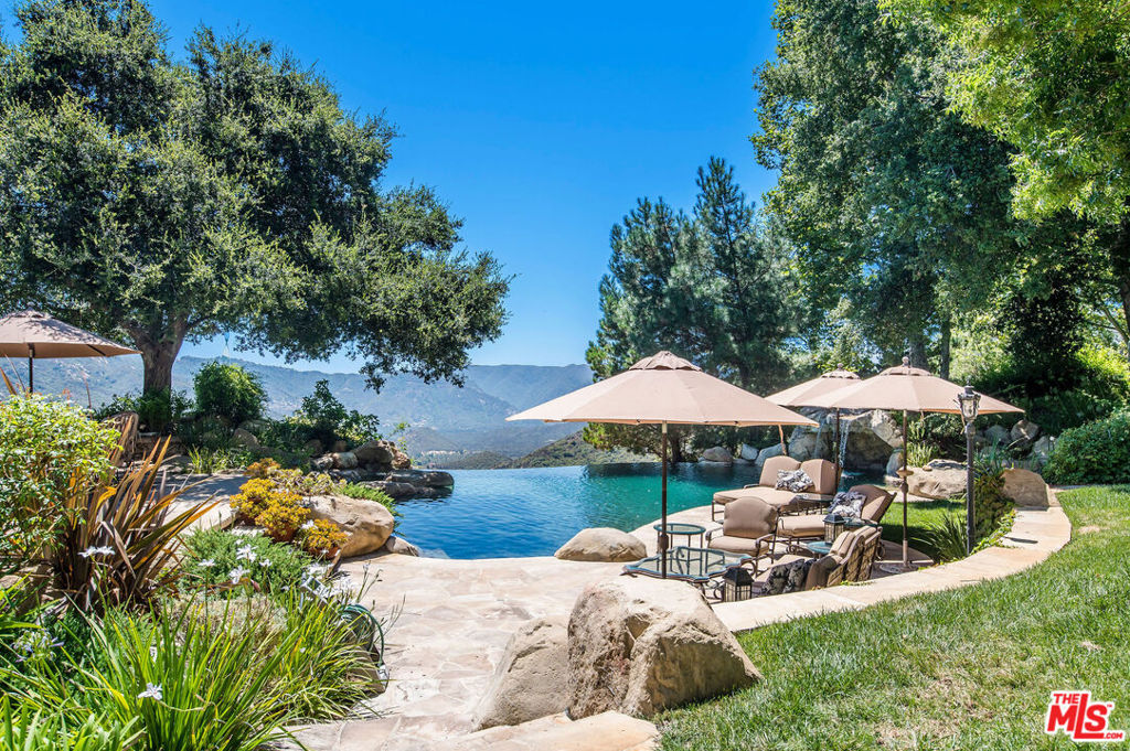 Stunning French-inspired Chateau situated on 10+ acres of serene park like grounds within the exclusive gated Calabasas enclave of Cold Creek Estates. Enjoy breathtaking and unobstructed canyon views from this remarkable residence, surrounded by the magical and unparalleled natural setting of the Santa Monica Mountains. This custom-built estate spans over 11,000 square feet of luxury craftsmanship meticulously designed and constructed to perfection. As you enter the double iron gates and stately motor court, this palatial storybook residence welcomes you. Throughout the interior, discover artisanal details such as intricately designed beamed ceilings, hand-distressed white oak flooring and custom solid wood doors and French imported hardware. Upon entering, the grand foyer flows seamlessly into the dramatic garden room conservatory providing a precursor view of the extraordinary gardens beyond. With 6 well-appointed bedroom suites, 11 bathrooms, subterranean stone wine cellar with tasting room and media/poker room, gym with private sauna, and a distinguished formal library, every corner of this home exudes refinement. The culinary chef's kitchen is well equipped with top-tier appliances including a La Cornue range, full size Sub Zero refrigerator and freezer, two dishwashers, warming oven, double wall ovens and two walk-in pantries. The expansive center island has a dedicated baking station, prep sink and breakfast bar. Enjoy the start of your day with coffee or tea in the sun-lit breakfast nook and end your day with a nightcap and Netflix by a warm fire in the adjacent den. Atop the floating staircase sits the impressive primary suite complete with private entry, three fireplaces and sitting room. The luxurious sleeping quarters are accentuated with volume coffered ceilings, fireplace and a private balcony that overlooks the expansive estate. The sumptuous primary bathroom offers dual vanities, spa soaking tub and warming fireplace plus a dressing room with dual walk-in closets and large makeup vanity. Additionally, the second level offers three en-suite bedrooms, ensuring ample space for your family and guests. The lush grounds are a true wonder, featuring an infinity-edge pool with waterfall grotto, spacious covered poolside pavilion with BBQ station, stone surround fireplace and a dedicated 3/4 bath plus changing room. A colorful English rose garden and vine-covered gazebo flank the meticulously manicured lawns, a serene koi pond and mature landscaping. Meandering pathways lead down to the greenhouse and citrus trees and invite exploration throughout the property. An elevator provides easy access across all levels, ensuring both luxury and accessibility. Other notable features include a caretaker's guest cottage, a rooftop observatory, ten uniquely designed fireplaces, imported slate roof and a four-car garage. This residence offers a truly extraordinary opportunity to own an estate that seamlessly blends luxury, craftsmanship, and the serene beauty of its natural surroundings.