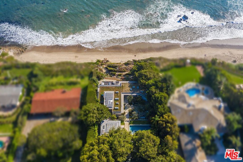 Mid-century modern elegance blends perfectly with 21st-century energy efficiency in this sleek, open, garden estate atop Encinal Bluffs. Exceptionally private, the approximately 1.89-acre blufftop property features majestic views of ocean and islands with resort-style amenities, including a detached guest house, sports court, solar-heated pool/spa, direct beach access, and guest parking for 20 cars. In 2009, W3 Architects stripped the original house to the foundation, reimagining and expanding the estate for sustainability and far-reaching vistas. Vanishing walls of glass open the spacious interior to gorgeous sight lines and beautiful decks, terraces, patios, pool, and gardens for refined indoor-outdoor relaxation and entertaining. Abundant natural light emphasizes the beauty of interior finishes, including stunning woodwork and cabinetry throughout. Pavilion-style living, dining, and kitchen spaces provide a harmonious setting for intimate gatherings and grand-scale entertaining. At the top of the beautiful wood staircase is a jewel-box surprise: a glass-walled loft for naps, yoga, and dreaming. The home's four en-suite bedrooms include a sublime primary retreat complete with a sitting area, an office with built-in desk and cabinets, a spa-style skylight bath, and pocket doors that open onto a large ocean-view deck. At the front of the house is a large garden, a tennis court set among statuesque trees and plantings, the pool, Jacuzzi, and spacious pool deck with a covered dining area, and the one-bedroom, one-bath guest house with a full kitchen. There is also an outdoor kitchen with a stone pizza oven and built-in dining area. In addition to an array of smart-home features, the estate is equipped with a photovoltaic array that supplies all the home's power needs, an active solar thermal water heating system for hot water and in-floor heating, plus an energy-conserving 3,000-square-foot planted living roof. A truly exceptional blufftop compound for a lifestyle of gracious contemporary comfort. Also available for lease at $50,000 per month.