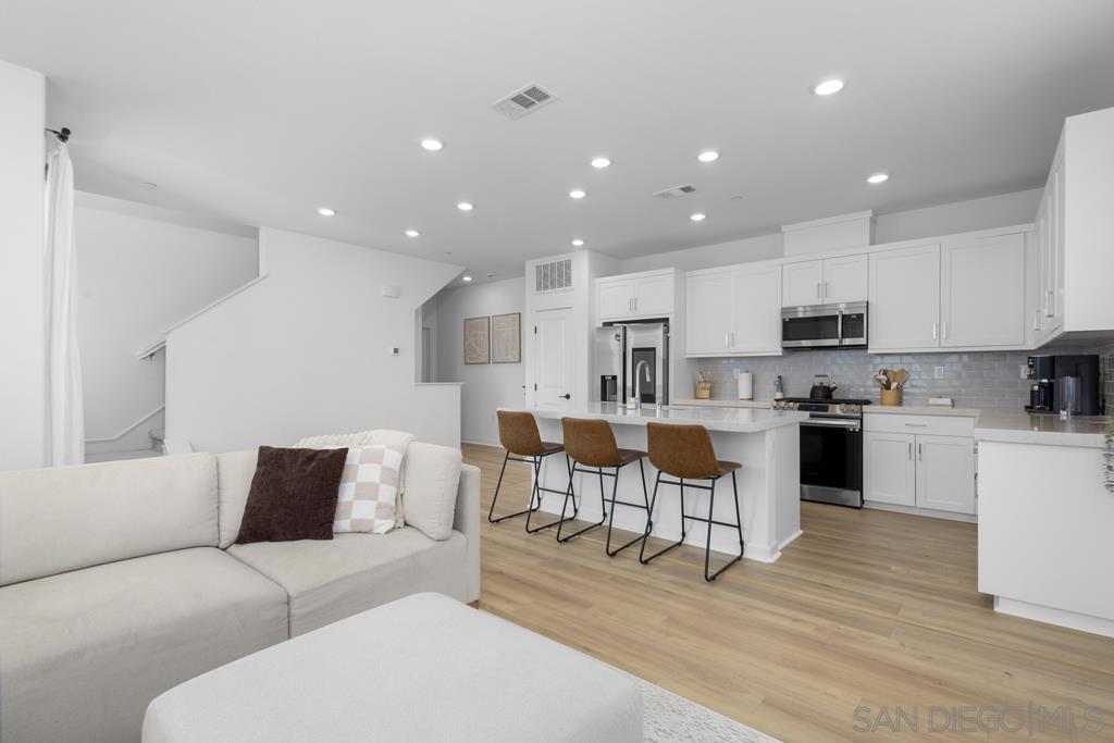 BRAND NEW LVP FLOORING! Welcome to this farmhouse-style CORNER townhome that offers a rare opportunity to own the largest floor plan in one of the San Diego's most exciting new neighborhoods. Inside, you’ll find a bright, open layout filled with natural light thanks to expansive south-facing windows. The first floor features a flexible BONUS SPACE with its own closet and half bath, ideal for a home office, gym, or easily convertible fifth bedroom. On the second level, you'll find a sleek modern kitchen with a gorgeous tile backsplash, a pantry, and new appliances, flowing seamlessly into the spacious living room. This level also includes a full bathroom, a bedroom, and a balcony for indoor -outdoor living. The top floor is home to a spacious primary suite with walk-in closet and large bath, two additional bedrooms, stackable laundry, and another full bathroom. Additional upgrades include OWNED SOLAR, roller shades, a side-by-side 2-car garage with EV CHARGING, and a peaceful corner-lot location with ample street parking. Enjoy access to beautifully landscaped green spaces and walkable parks, with Epoca’s resort-style pool, fitness center, and clubhouse coming soon. With lower HOA fees, lower Mello Roos, and a community that hosts regular food truck nights and neighborhood gatherings, this home offers it all!