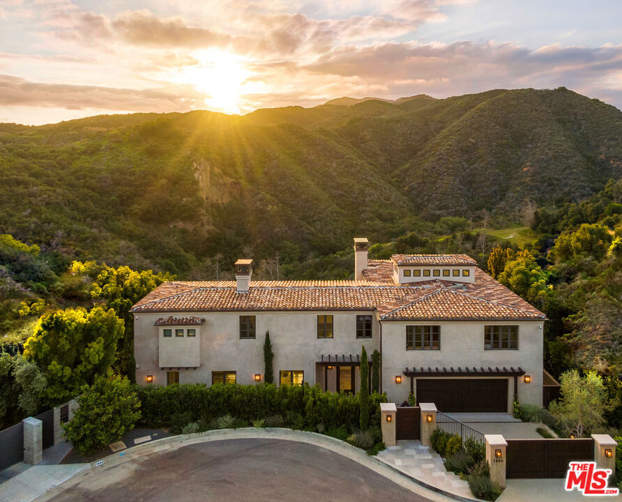 Welcome to 1505 Umeo Road, an exquisite private residence set in a rare and extraordinary location overlooking the magnificent Santa Monica Mountains. This gated, upper Riviera estate has undergone a complete transformation, showcasing a cultivated and classic European charm with a refined modern elegance. When strolling the property it is evident that every detail has been carefully crafted and meticulously designed. Step inside and be greeted by a rich and spacious living room, with adjoining powder room and wet bar, ideally flanked by a row of French doors that open onto the back terrace and pool while simultaneously offering panoramic views of the spectacular mountain range. Anchoring the space and adding a touch of grandeur is the impressive sleek fireplace framed by an understated sculpted limestone surround. Opposite the living room is the family room, chef's kitchen and adjacent butler's pantry which, again, seamlessly connect to the outdoor deck and pool creating the perfect environment for entertaining family and friends. Following the harmonious indoor-outdoor flow of the living and family spaces you are effortlessly led to the beautiful rear courtyard where you'll discover a stunning infinity-edge pool with sunken spa, outdoor kitchen, cozy fireplace and lovely pool bath. The serene outdoor oasis beckons and entices you to relax and enjoy the natural beauty that envelopes the estate. Upon wandering back inside, when ascending the staircase to the upper level take a moment to admire the bespoke ironwork railing and breathtaking light-filled cupola which bathes the home in glowing warmth and welcoming ambiance. Situated on this upper level is the master along with two generously sized bedrooms each with its own ensuite bath. The sumptuous primary suite is a true retreat, offering exquisite views, a generous fully customized walk-in closet with superb dressing room and a luxurious bathroom complete with an enormous steam shower, soaking tub, heated floors and dual vanities. Moving to the lower level one finds a well-appointed and spacious laundry room with an abundant amount of storage, a wine room and sizeable fourth bedroom with large walk-in closet. This large bedroom with ensuite bath and spectacular outdoor terrace could easily be transformed into a home gym, yoga studio, lavish office or entertainment area. Along with the countless amenities this residence provides it also comes equipped with the latest in technological advancements including state-of-the-art security and cameras, a Savant Pro Smart Home System and automated Lutron lights and shades. Further refinements include the hand-selected and fastidiously installed French limestone and European Oak flooring throughout; custom light fixtures; four fireplaces; a generator; a substantial and versatile bonus area beneath the lower deck and an elevator servicing all three levels. Come experience the epitome of luxury and tranquility in this exceptional and stunning home discretely nestled in the prestigious Los Angeles neighborhood of Pacific Palisades and be swept away into a private world of timeless European elegance perfectly blended with the finest of contemporary living.