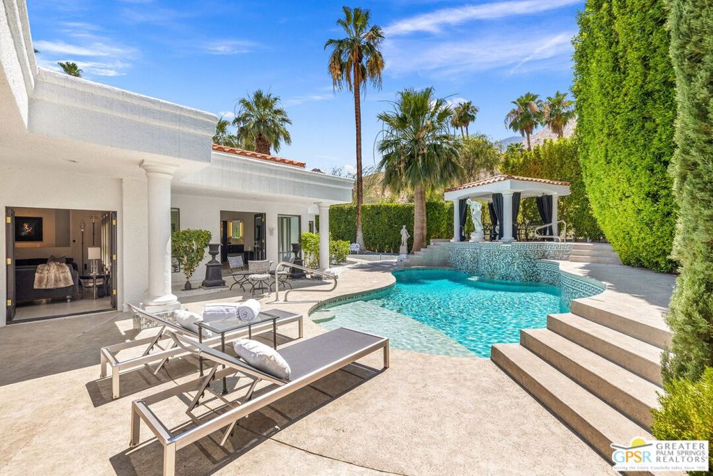 A Magical Setting in The Mesa! Perfectly positioned in one of South Palm Springs' most cherished and storied neighborhoods, this elegant 4 BED, 4.5 BATH residence offers a seamless blend of style, comfort, and desert sophistication. Set on land you own (Fee Simple) with OWNED SOLAR, the property features a circular driveway leading to a beautifully appointed 4 bedroom ensuite home. Designed for both everyday luxury and entertaining, the residence wraps around a stunning pool and spa with waterfall, dramatic mosaic tile accents, an elevated gazebo framed by mountain views and swaying palms. Multiple outdoor conversation areas enhance this ultra-private setting. The gated courtyard entry and double doors open to formal living and dining spaces with dual fireplaces and a custom bar area, also ideal as a destination-style media lounge. Notable lighting throughout includes Baccarat fixtures that complement the home's subtle nod to Hollywood Regency design. The chef's kitchen features high-end finishes, a generous buffet, walk-in pantry, and breakfast area with patio access. The spacious primary retreat offers direct pool access, a Carrara marble-lined shower, and a freestanding clawfoot tub. Two additional guest suites are thoughtfully positioned along the west wing, each with private full baths. The attached casita, located in the east wing, features two sets of French doors that open to the outdoors and floor-to-ceiling built-in bookcases. This generous space functions beautifully as a second primary suite or private retreat.Additional highlights include a large utility room, direct garage access, and a secondary entrance off Carmelita Street, perfect for pool guests or staff. Take the Matterport Virtual Tour to experience the flow and finish of this exceptional South Palm Springs property.