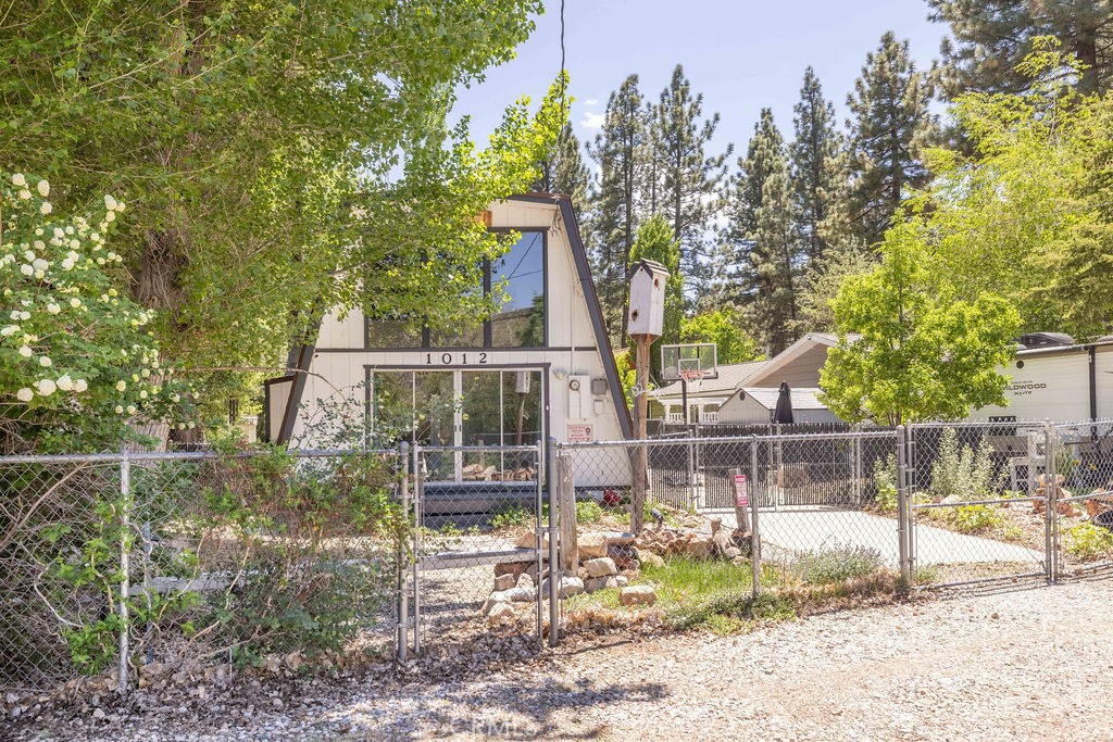 Located in the quiet Shay Meadow neighborhood of Big Bear City, this modified A-frame cabin stands out with its bold architecture, open layout, and inviting outdoor space. With 2 bedrooms (including an upper loft-style bedroom), 1 bathroom, and a 5,500 sq ft lot, this home blends cozy character with practical features for everyday living or weekend escapes. Inside, vaulted wood ceilings and floor-to-ceiling windows fill the living room with mountain light and warmth. The stone fireplace adds a rustic focal point, while the kitchen features matte black cabinetry, and modern appliances—creating a space that feels both functional and authentic. Upstairs, the open loft offers flexibility for sleeping, lounging, or game nights, currently outfitted with a pool table and ample space to relax. Out back, a spacious deck, spa, and grassy yard invite connection and downtime. Two storage sheds, RV or boat parking, and fencing on all sides offer both convenience and privacy. Seasonal landscaping and mature trees add natural beauty, and open views of Shay Meadow give the yard a peaceful, expansive feel. Whether you're setting down roots, investing in a short-term rental, or looking for a personal getaway, this property offers charm, function, and that unmistakable Big Bear lifestyle.