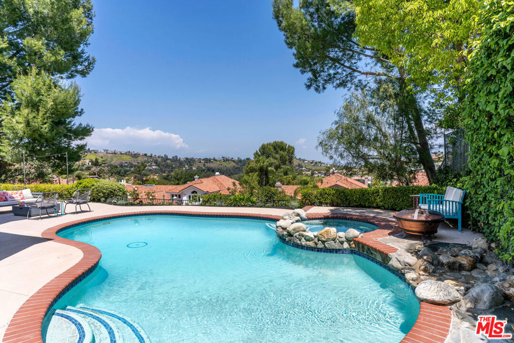 Discover refined luxury living in one of Calabasas' most prestigious enclaves, the exclusive double-gated Calabasas Park Estates. This sophisticated 5-bedroom estate residence, situated on a highly desirable elevated lot, commands breathtaking panoramic views of Calabasas and the surrounding hills, offering an unparalleled connection to Southern California's most coveted natural landscape. Priced competitively within this sought-after community, this home represents the perfect harmony of luxury and natural beauty. The estate's elegant floor plan unfolds with a dramatic travertine-clad entry, flowing into elegant living spaces adorned with engineered wood floors and French doors that blur the line between indoor and outdoor living. The gourmet chef's kitchen, complete with premium stainless steel appliances and a generous island, serves as the heart of the home, while two inviting fireplaces add warmth and sophistication to both the living room and family room. The primary suite epitomizes luxury with its private fireplace, sitting area, dual closets, and spa-like bathroom featuring a spacious tub and dual vanities - all enhanced by sweeping views of the estate and the nearby Calabasas Country Club grounds. Four additional bedrooms, including a private first-floor suite perfect for guests or multi-generational living, complement the home's impressive amenities, which include an office, playroom/den, pantry, laundry room, and direct access to the 3-car garage. The resort-style backyard stands as an entertainer's paradise, boasting a sparkling pool and spa set against a backdrop of panoramic mountain vistas. This outdoor sanctuary provides the perfect setting for both intimate gatherings and larger scale entertaining. Located within the prestigious Calabasas community, residents enjoy access to exclusive amenities including tennis courts and meticulously maintained grounds, all protected by 24-hour guard-gated security. The home's prime location offers easy access to Blue Ribbon schools, upscale shopping and dining at The Commons, and world-class hiking trails, with close proximity to both the scenic Malibu coastline and the beautiful Santa Monica Mountains. Experience the pinnacle of Southern California luxury living in this exceptional estate property. This property is also available for lease.