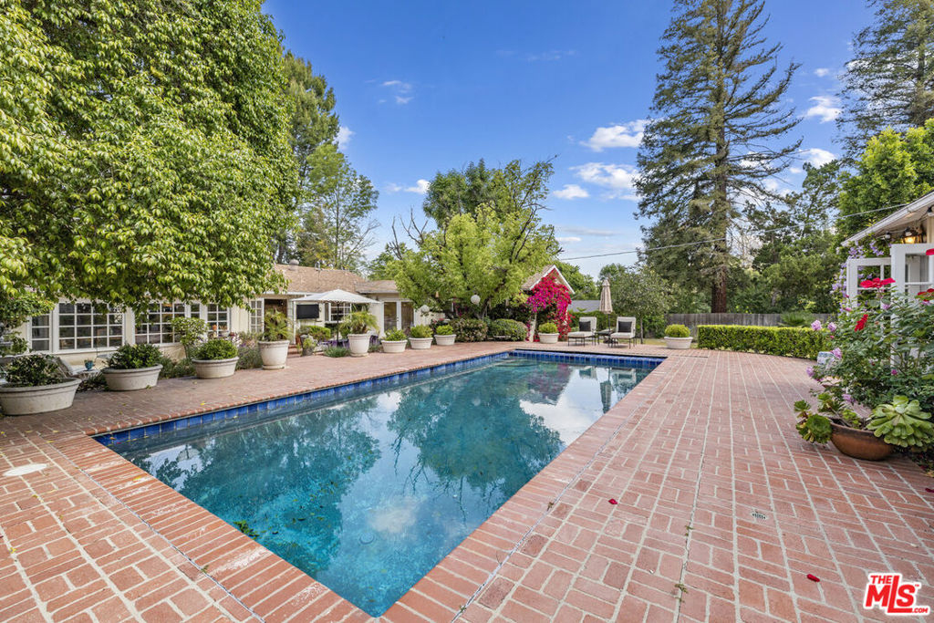 Must see to appreciate this prawling SOB gated single-story estate. The classic charming white picket fence surrounds an expansive lush front yard. Inside the home features an open, airy layout with spacious living areas, large windows offering abundant natural light, and seamless indoor-outdoor flow. Perfect for large gatherings or creating those small memorable moments curled up by the fire. The light and bright kitchen with eat in space by it's fireplace, is situated perfectly to the elegant outdoor brick BBQ and dining area. The considerable dining room with its multitude of windows is conveniently located just off the family room with brick fireplace and overlooks the backyard. The primary suite, one of four in the main house, with high ceiling and remodeled bath is located in the back of the home offering a peaceful retreat at days end. This compound offers the quintessential So Cal Indoor Outdoor lifestyle. You'll enjoy these upcoming warm summer days and the cool nights relaxing or entertaining in the great outdoors by the pool. The sun filled ADU has French doors and vast windows that make it a welcoming living space. Plenty of room to roam and yet still enjoy the luxury of privacy throughout this 19k+sf all flat lot. The expansive lot includes lush landscaping, a large backyard, a swimming pool, and plenty of outdoor entertaining spaces. All this in a serene, prestigious neighborhood setting yet close to award winning schools, fashionable shopping, fine dining, plus a multitude of recreational activities, all just moment away. Don't miss this opportunity that captures the essence of prominent suburban living.