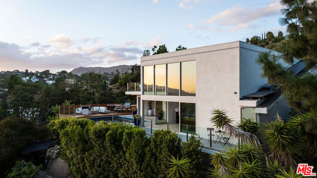 Set behind the gates of an exclusive enclave in Valley Oak, this meticulously reimagined 1960s contemporary architectural showpiece offers unparalleled privacy and sophistication. Designed by renowned architect Tim Campbell to complement its prestigious location, the home welcomes you through a serene fountain courtyard into a two-story open floor plan bathed in natural light. Blonde maple floors and floor-to-ceiling windows frame panoramic views of Los Angeles at every turn. The sleek kitchen, equipped with high-end finishes and appliances, flows effortlessly into an open dining space and seating area. With disappearing sliding doors, lay by the pool inside the media room/den complete with a wet bar, stone tile flooring and full bath, the perfect setting for entertaining. Upstairs, the primary suite is a tranquil retreat, featuring an oversized balcony overlooking the entertainer's yard and the glittering cityscape. The spa-like primary bath offers a Jacuzzi tub, steam shower, and sliding mirrors to ensure the breathtaking views are never missed. A spacious walk-in closet completes this private escape. The upper level also includes two guest bedrooms with a shared bath, while a third en suite bedroom on the main floor provides ample space for family or guests. Outside, the property amazes with a saltwater negative-edge pool and spa, perfectly positioned to capture the stunning vistas. An Ipe wood deck, outdoor dining area, grilling station, shower, and fireplace set the stage for unforgettable gatherings, framed by iconic views of Los Angeles. Additional features include a Savant smart home system, Lutron automated blinds, multi-room audio, comprehensive security, and a two-car garage with direct access. This is a rare opportunity to own a home that embodies the essence of privacy, luxury, and architectural significance nestled in one of LA's most prestigious gated neighborhoods. The perfect package.