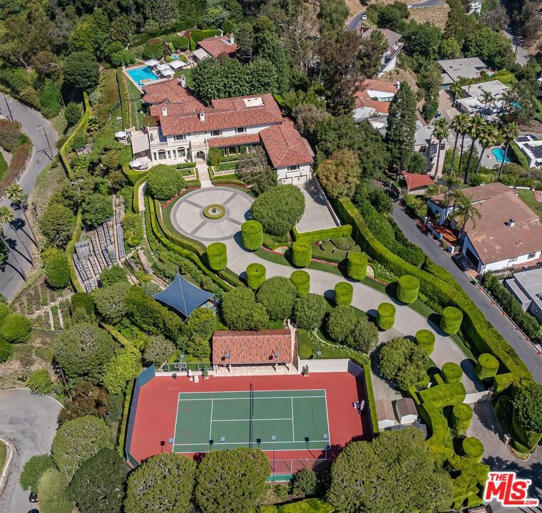 A legendary Beverly Hills estate with rich Hollywood lore, set on its own private 2.37-acre mostly flat promontory with head-on ocean and city views, is now offered following a multi-year renovation and reimagining. Located adjacent to the Pritzker, Murdoch, and future Gates family estates, this Modern Tuscan masterpiece was home to Ricky Martin for many years and previously owned by English actor Michael Caine. Prior to the Caines, the estate was owned by Doris Day's family. Poised behind tall gates and approached via a long, curving, tree-lined drive, the property unfolds into a sprawling motor court with parking for 20+ cars. The grounds include a luxurious main residence, guest house, lighted tennis court with pavilion, separate children's playground and play court, and a dedicated security house - all surrounded by vast lawns, lush gardens, and mature landscaping. An orchard, herb and cutting garden, and a separate rose garden provide fresh flowers and fruit. From the moment you arrive, the most striking feature is the panoramic views - stretching from Mid-Wilshire, over Santa Monica and the ocean, all the way up the coast to Malibu. These sweeping vistas can be enjoyed from nearly every part of the estate, including all the primary rooms, patios, yards, and terraces. Even the pool is positioned to allow for ocean views while swimming. Exceptional privacy is ensured, with no neighboring homes overlooking the property. The main residence, while expansive, is thoughtfully designed for comfortable family living. A grand kitchen/living/great room opens directly to the pool area, lawns, and breathtaking views. An oversized theater is richly appointed and includes a snack room and two powder rooms. Each bedroom offers views - either of the ocean and city or tranquil garden settings. The bright and elegant primary suite features its own terrace with city and ocean views, a sitting room, dual bathroom and dressing areas, oversized closets, and a large flexible space ideal for a nursery, massage room, office, or additional wardrobe. State-of-the-art home, perimeter, and grounds security systems are actively monitored from the security house, with additional measures discreetly integrated into the main residence. This exceptional Beverly Hills estate offers an unmatched combination of privacy, history, and panoramic views presenting a rare opportunity to own one of the area's most storied and breathtaking properties.