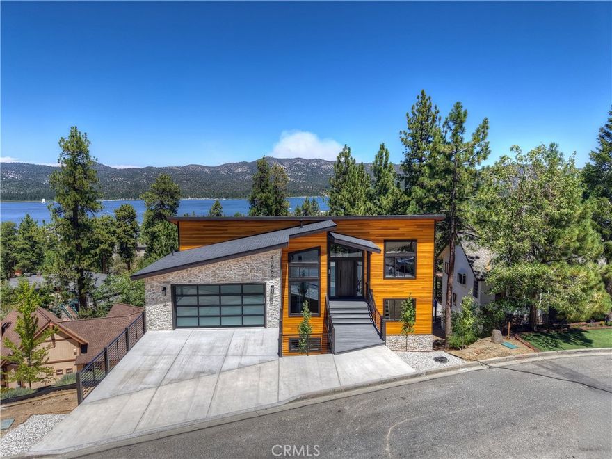 Located in sought-after Ironwood Estates, this magnificent BRAND NEW CONSTRUCTION is strategically positioned just behind the Village on a STREET-TO-STREET lot and boasts BREATHTAKING VIEWS of BIG BEAR LAKE! Prime location with just a short drive to the Village, restaurants, lake and ski resorts, this rustic contemporary home is truly stunning ~ As you enter the open living room, you'll be immediately drawn to the panoramic lake views ~ Large open living room and kitchen with big Anderson picture windows ~ Knotty alder tongue and groove ceilings, walls and doors, lots of cabinetry with a center island, stainless steel appliances (Decor fridge, range, microwave, & dishwasher) and granite slab counters ~ Primary suite on main floor with the fireplace and ensuite bathroom with barn door ~ Huge family room downstairs perfect for entertaining large groups with potential for a movie theater (prewired) plus another 3 bedrooms, and a gathering area and bedroom on the bottom floor (a total of 3 suites - 1 on each floor) ~ Separate laundry room ~ Wine cellar ~ Convenient level entry to an oversized 2 car attached garage ~ Other modern amenities include a tankless water heater, fire sprinklers, electrical wiring in the garage for EV charging, and solar panels (owned, not leased) ~ Expansive decking with views of the lake, mountains and valley ~ Additional off-street parking on back side of the property with a newly terraced yard ~ Home was just recently completed ~ Come experience everything this extraordinary brand new home has to offer!