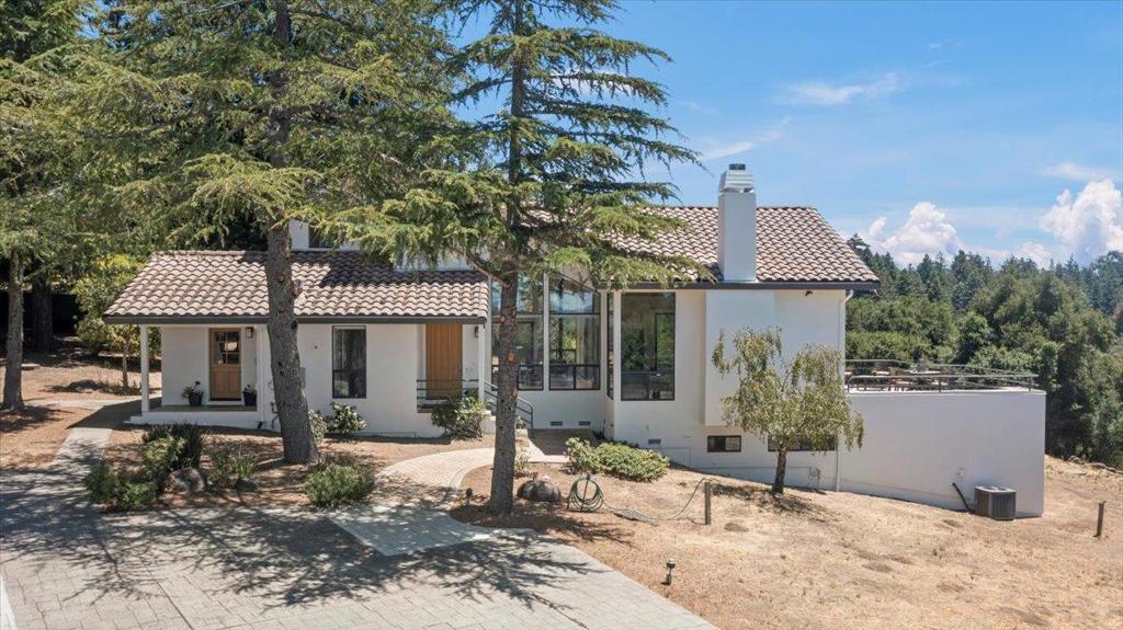 Remarkable mountain property with stunning Monterey Bay and long-range mountain views! Set on approximately 2.45 acres, this exceptional retreat offers privacy, usability, and breathtaking scenery. The property features a fenced pasture, fruit trees, and raised garden beds, ideal for a sustainable lifestyle. Inside, vaulted ceilings and expansive windows fill the home with natural light and frame spectacular vistas. The gourmet kitchen boasts a gas cooktop, KitchenAid oven, and abundant windows looking to the bay. A welcoming living room offers vaulted ceilings, a cozy fireplace, and access to two private decks. The main level includes a spacious dining room with soaring ceilings, a large bedroom, full bath, laundry room, and a mudroom. Upstairs, the modern primary suite provides a serene retreat with a private deck and sweeping views. The lower level offers a private suite with a luxurious bath and separate entry, ideal for guests or extended family. Additional highlights include a detached 4-car garage with wine storage and an unfinished bonus room above, owned solar with backup batteries, Comcast internet, and proximity to top-rated schools: Loma Prieta Elementary, C.T. English Middle, and Los Gatos High. Easy access to Summit Store and coastal beach towns.