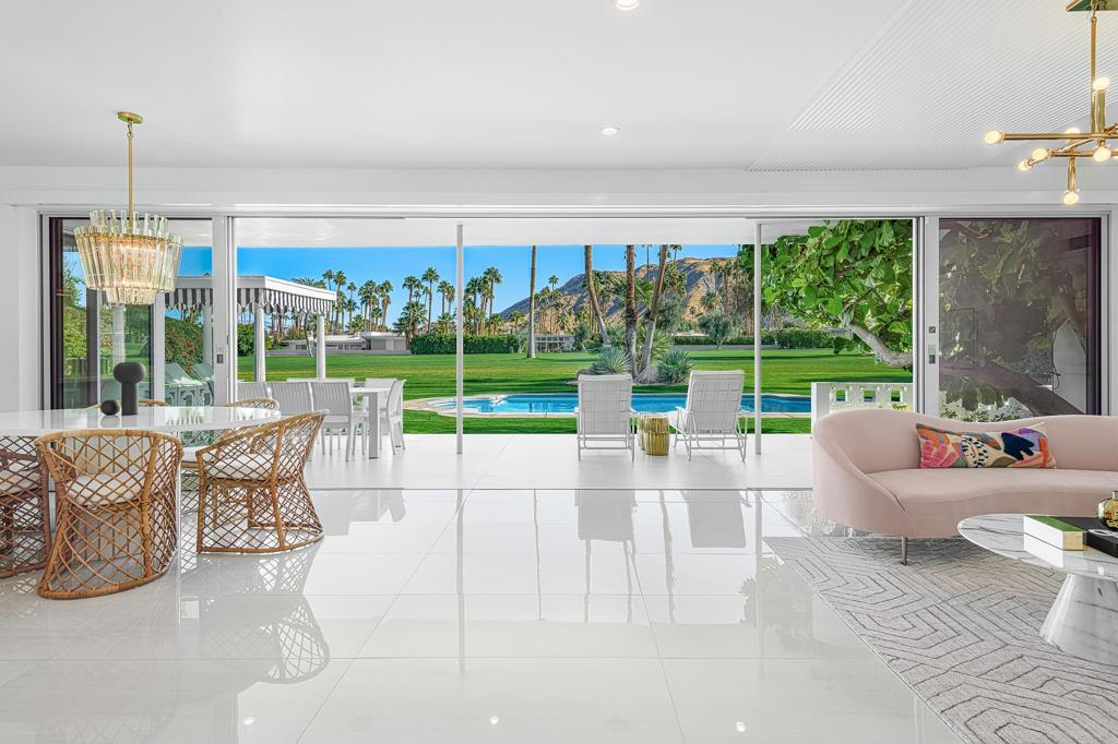Indulge in the flawless fusion of Hollywood Regency and Mid-Century Modern in this reverently and masterfully remodeled oasis. This storied home, previously owned by the Chasen family (famous Beverly Hills restaurateurs), is nestled within the coveted Indian Canyons Neighborhood in South Palm Springs and was meticulously crafted by renowned Architect Raymond Levanas in the 1960s before being fully renovated by the owners in 2020-2022 with the assistance of acclaimed local designer Michelle Boudreau. Featured in Modernism, this luxurious 4 bedroom, 4 bath sanctuary embodies the architect's original vision while seamlessly integrating upscale contemporary finishes. From the champagne bubble breeze blocks to the terrazzo entryway to the epic mountain views visible from every single room, each thoughtful detail of the home sets the stage for an extraordinary living experience. The living room's captivating fireplace, adorned with a Bauhaus slat design carried above the ceiling, beautifully echoes the sleek aesthetic found throughout the home. The gourmet kitchen is a perfect blend of functionality and style, fully equipped with Subzero/Wolf appliances including a column wine fridge, refrigerated beverage drawers, built-in coffee maker, and a drawer microwave. The premium appliances are beautifully complemented by custom oak built-ins and elegant onyx marble countertops, creating an ideal space for crafting gourmet meals and entertaining guests. Relish in the abundance of natural light that cascades through the floor-to-ceiling Fleetwood sliders, offering mesmerizing vistas of the Indian Canyons Golf Course and majestic mountains. All bathrooms have undergone a spa-like renovation. The primary suite boasts a sitting vanity between the double sinks as well as both an indoor and outdoor shower and an indulgent outdoor soaking tub, ensuring an elevated level of luxury. Temperature controlled two-car garage with new epoxy flooring and a built-in electric charger, and a spacious mud/laundry room with a built-in pebble ice machine. Step outside to the inviting backyard that seamlessly cascades out to the golf course to create the illusion of infinite outdoor space to enjoy two beautifully restored twin pergolas that frame a Hollywood Regency shaped pool with original turtles that were the signature of the home's renowned architect, a dining space next to the kitchen by a thriving fiddle fig tree and fragrant gardenias and a citrus grove. No expense has been spared!