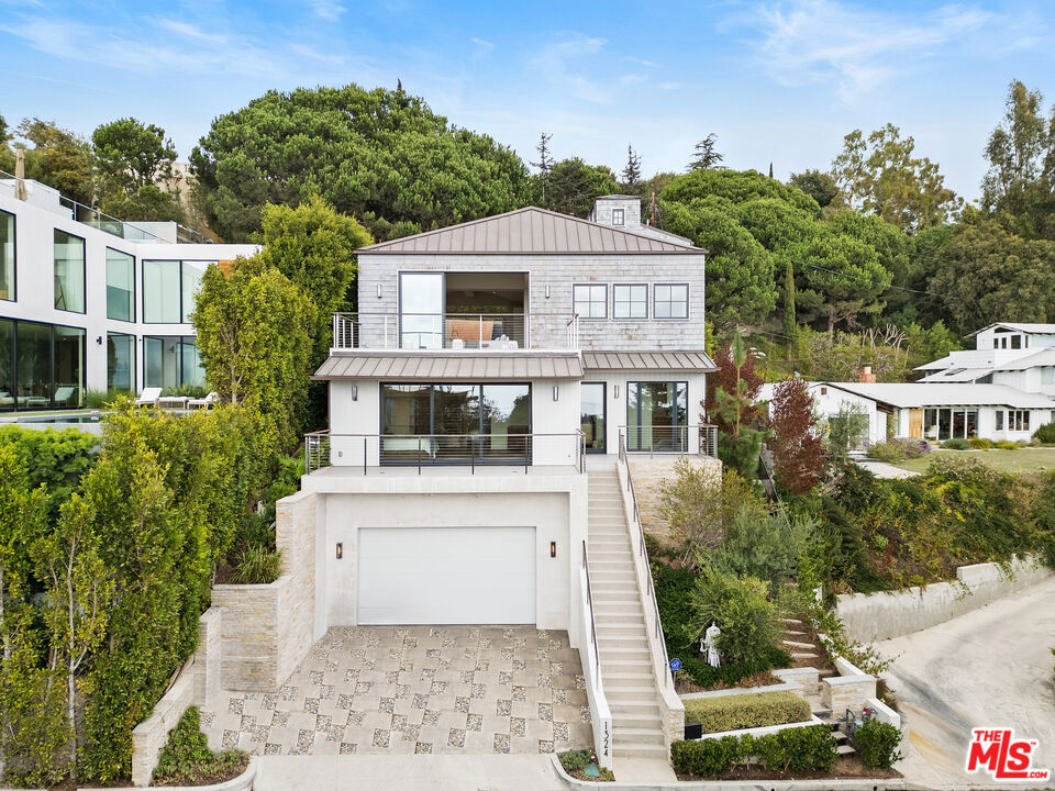 No need to rebuild, this home is ready now! Perched on a quiet street above the Palisades Village, this stunning Cape-Cod inspired residence built in 2019 offers sweeping views of the Pacific Ocean and the city skyline. Thoughtfully designed across three expansive levels, this stunning contemporary masterpiece features 5 bedrooms, 7 bathrooms, and effortlessly blends refined interiors with seamless indoor-outdoor living. Crafted for modern living, this smart home includes a spacious media room with wet bar, a sparkling pool and spa, and an expansive rooftop deck showcasing spectacular ocean vistas. The gourmet kitchen flows into both the private backyard and the elegant formal dining and living areas, complete with a fireplace and a sunlit terrace. The luxurious primary suite is a tranquil retreat, boasting panoramic ocean views from its private patio, a cozy fireplace, an oversized walk-in closet, and a spa-inspired bathroom with steam shower and soaking tub. Each additional bedroom is en suite, offering privacy and comfort. Additional highlights include an oversized two-car garage, a private elevator, full laundry and utility rooms, and smart-home technology throughout. Located in the coveted Alphabet Streets of Pacific Palisades, this exceptional home is just moments from the shops, restaurants, and charm of the Palisades Village.