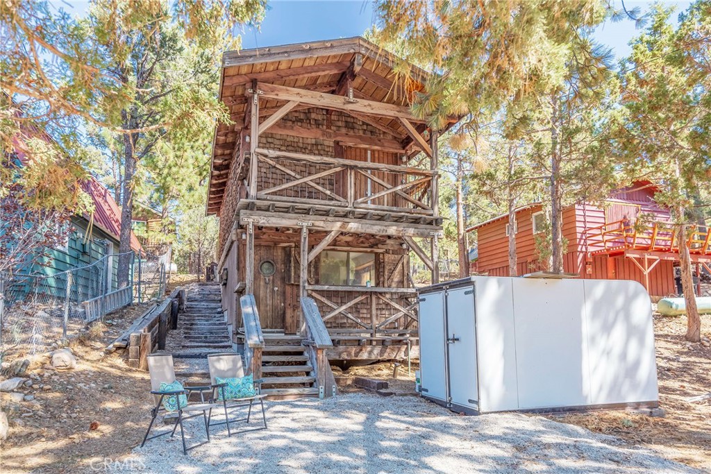 This 2-bedroom, 1-bath cabin on a 2,500 sq. ft. lot, nestled amid mountain beauty and mature trees, blends whimsical charm with enduring craftsmanship—offering a wonderful opportunity for your next mountain retreat or investment. Built as the personal passion project of a contractor/carpenter known for the beauty of his spiral staircases—this home showcases both craftsmanship and integrity. Amazingly thick wood doors pair with commercial-grade lock systems, industrial-style hardware, and a fire suppression system in the rear yard, underscoring a home built to last. Rustic wood and metal details highlight the cabin’s mountain character, with craftsmanship adding warmth and charm. Inside, each bedroom features open wood-beam ceilings, unique light fixtures, and well-sized closets, while the front bedroom opens to its own upper balcony overlooking the front yard. The 2nd bedroom’s double doors provide access to the rear. This home is full of character—ready and waiting for the next owners to add to its special nature with their own vision. A covered front porch frames the yard, and a free-standing locked storage unit offers space for tools, gear, and toys. Good, level parking adds convenience to mountain living, and the home itself is loaded with potential. Sugarloaf’s small-town charm is just minutes away with Kallan’s Bar & Grill, the local park, fire station, post office, and neighborhood market, while Big Bear Lake, ski resorts, and Big Bear's Village with its shops, restaurants, and year-round entertainment are just a short drive. A truly unique property ready for you to make it your own!