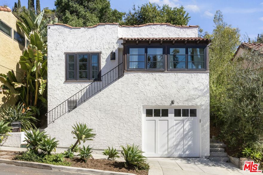 Have it all in Silver Lake with this 1925 Spanish, a private hillside retreat filled with sunlight, character, and thoughtful updates. The light-filled living room is a warm, inviting space with built-ins and an arched passthrough to the charming dining room; wood floors flow throughout. Meal prep is easy in the bright galley kitchen, finished with quartz countertops, stainless appliances, and a walk-in pantry with laundry. Two bedrooms include a serene ensuite primary with a walk-in closet and a remodeled bath, plus a powder room for guests. The lower suite with a separate entrance and bath adds flexibility for visitors or creative work. The lush, secluded yard feels like an idyllic escape with terraced gardens, mature trees, and plenty of space to dine, lounge and gather. Amenities include HVAC, laundry, and a garage with storage. From this tranquil perch, you're moments from Bar Siesta, L&E Oyster Bar, Lamill Coffee, and the Silver Lake Reservoir.