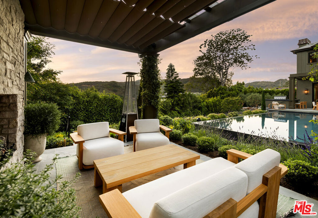 Perfectly situated in the coveted Pacific Palisades Riviera and set behind gates amidst lush and spectacular landscaping is this remarkable estate. The flawlessly executed interiors created by the renowned interior design firm Pierce and Ward, along with the home being a newly built Ken Ungar estate, make this home truly-one-of-a-kind. Every inch of the home, inside and outside, has been transformed to capture the striking canyon views and beams of light glowing through soaring windows and doors from sunrise to sunset at carefully designed vistas throughout the day. Enter through a stunning glass door to ultra-inviting living and dining rooms designed for daily enjoyment, with lavish yet welcoming interiors that appeal to all, featuring a London-chic flair mixed with mid-century design that will surely rival the best home designs executed in all of Los Angeles. The super-inviting family kitchen, with double banquet nooks you won't want to leave all day, offers counter seating, a top-of-the-line Wolf range, multiple ovens, double sinks, and wall-to-wall refrigeration, all opening to a large, stunning family room reminiscent of a chic boutique hotel. This space seamlessly transitions to a large outdoor dining table and chef's barbecue area, ideal for cooking and entertaining guests, all with stunning canyon views. The first floor also features a tucked-away office and a spacious downstairs suite, all carefully laid out with the architect's clear understanding of a masterful floor plan. The second floor boasts a primary suite tucked in its own wing, with dual doors, a fireplace, two walk-in closets: one on each end, a luxurious bath suite, for two, with an oversized double shower, soaking tub, two water closets, separate sink areas, and make-up seating for her, all with beautiful views of the meticulously landscaped grounds and a balcony completing this truly intimate and cozy suite. Across the landing, the second floor also offers a cozy upstairs family room set between three suites, each designed with extraordinary interiors and beautiful tree-top views. An elevator services all three floors, including the lower level, which features the single most inviting screening room, clearly designed for family and friends' movie nights. The lower floor also boasts a large open family room/pool and game room, a stunning bar area, and a wine room, all opening to a cozy patio with plenty of room to enjoy a cold plunge after Pilates in the custom-designed double studio suite and sauna. Down the hall, there is a jaw-dropping four-bed bunk room suite, perfect for late-night sleepovers or additional holiday guests. To complete this lush estate, there is an infinity-edge pool, oversized Baja shelves and spa, a built-in trellis with a fireplace, and a lower-level multiple seating area for guests, parties, and late-night conversations in this award-worthy landscape design encasing the entire estate. Simply exquisite and clearly one of Pierce and Ward's finest design and landscape visions.